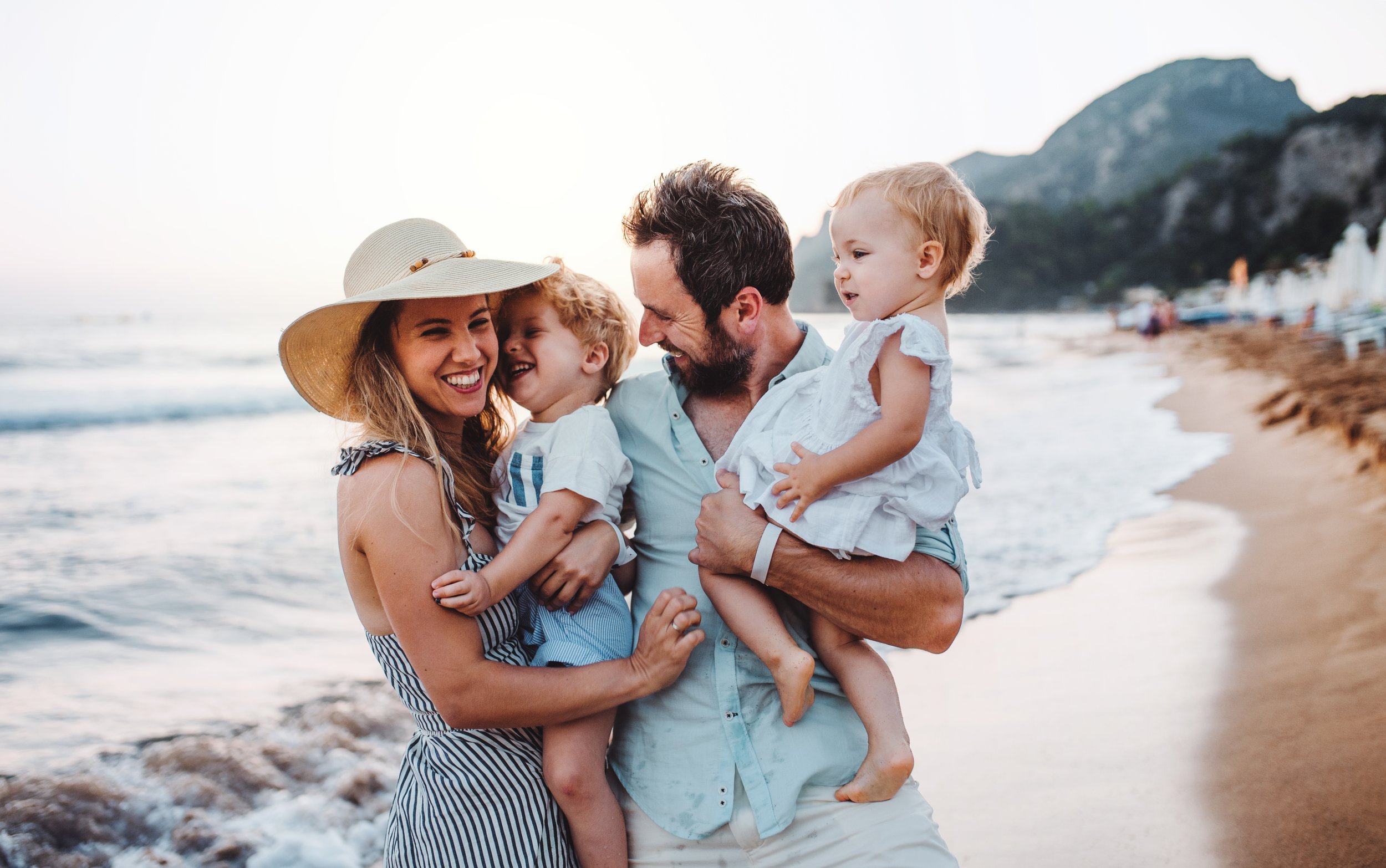 “Happy family with two small children enjoying a walk together along the beach