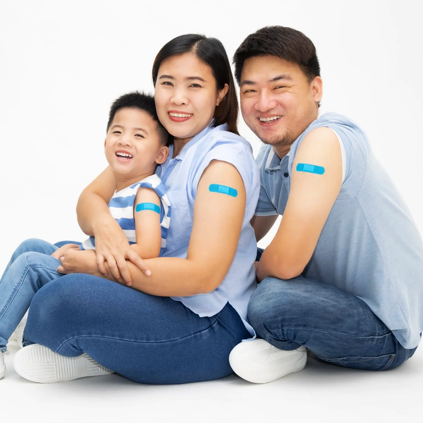 Family of three smiling with bandages on their arms after receiving flu vaccinations