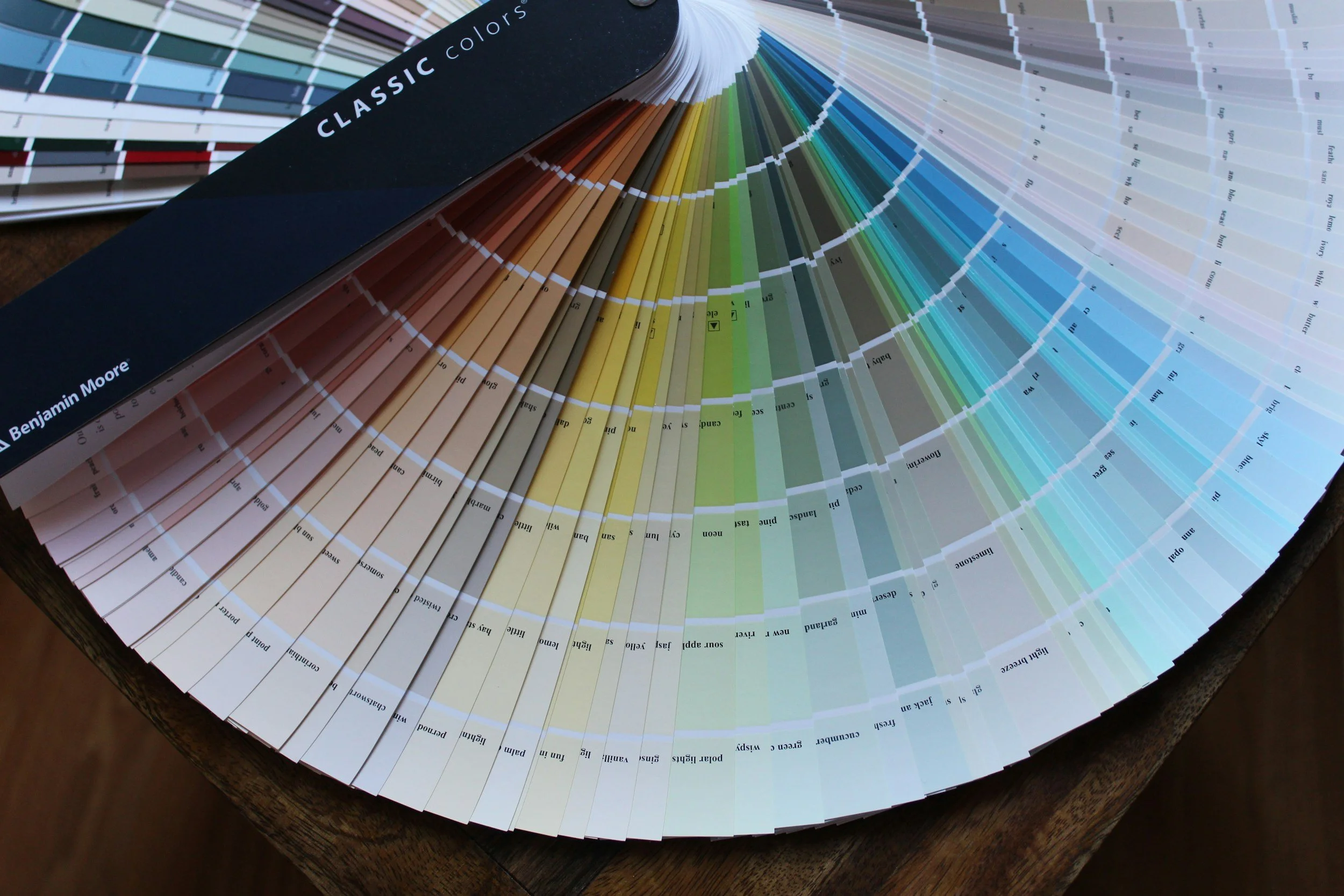 A color fan deck displaying various shades of paint colors arranged in a circular fan shape, with text indicating color names and codes.