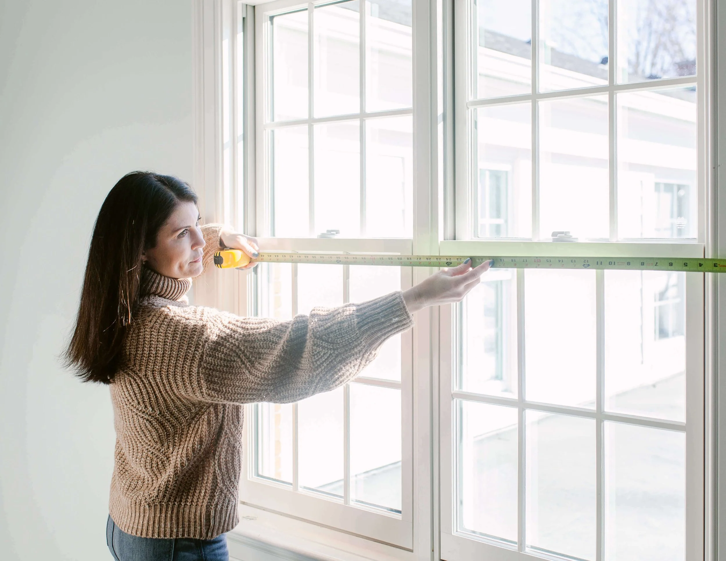Dana Newsom measuring a client's window