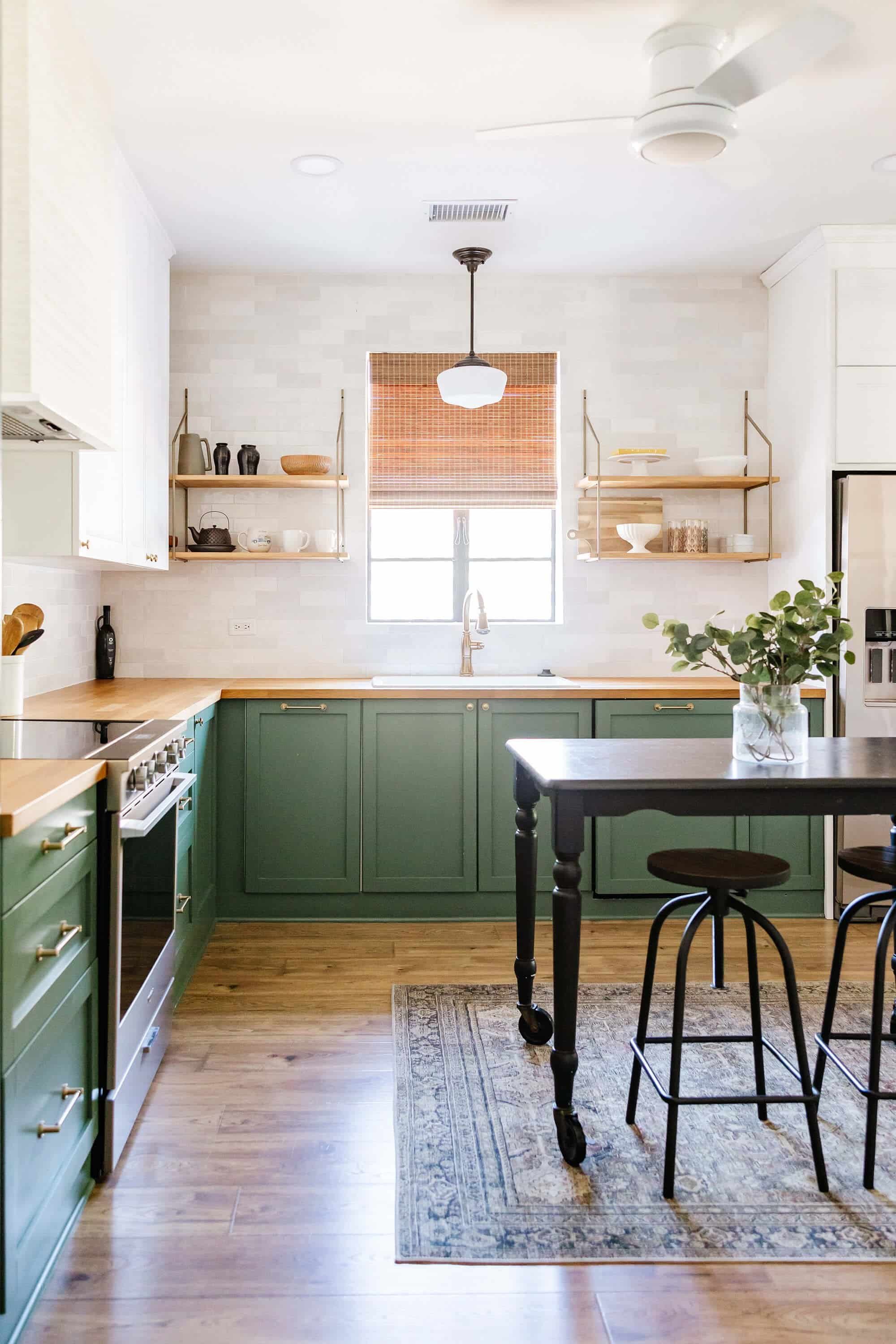 Woven wood shade in a kitchen with charming green cabinetry