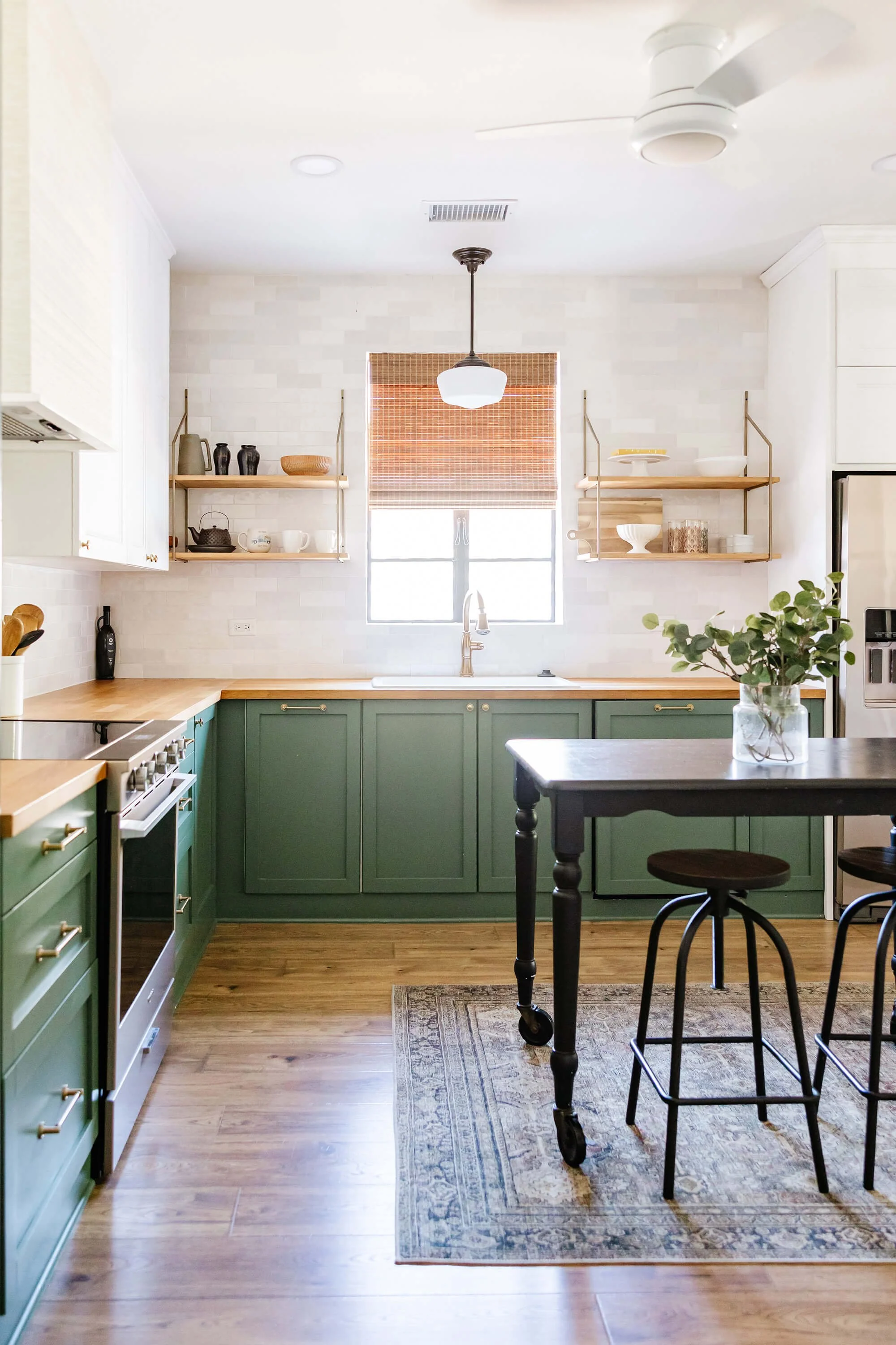 Woven wood shade in a kitchen with charming green cabinetry