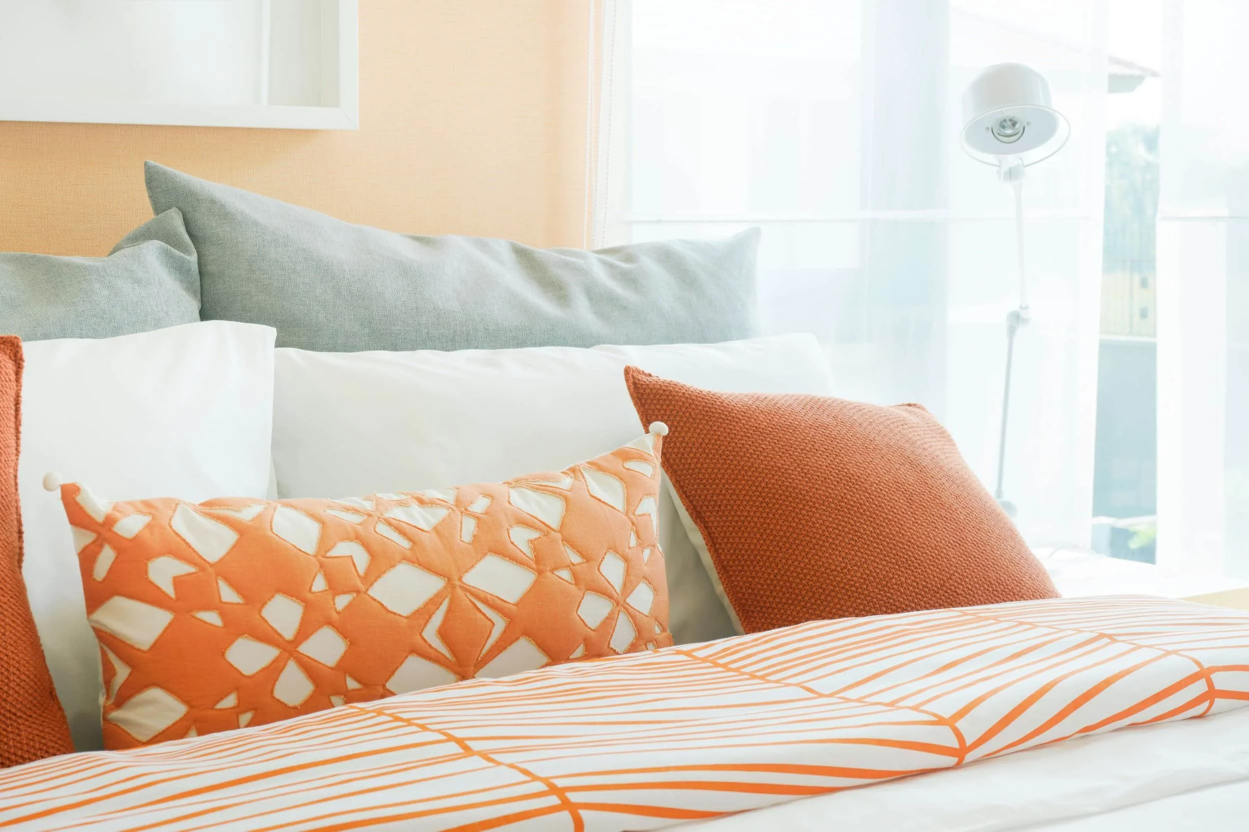 Designer bedding and custom pillows in oranges and teals