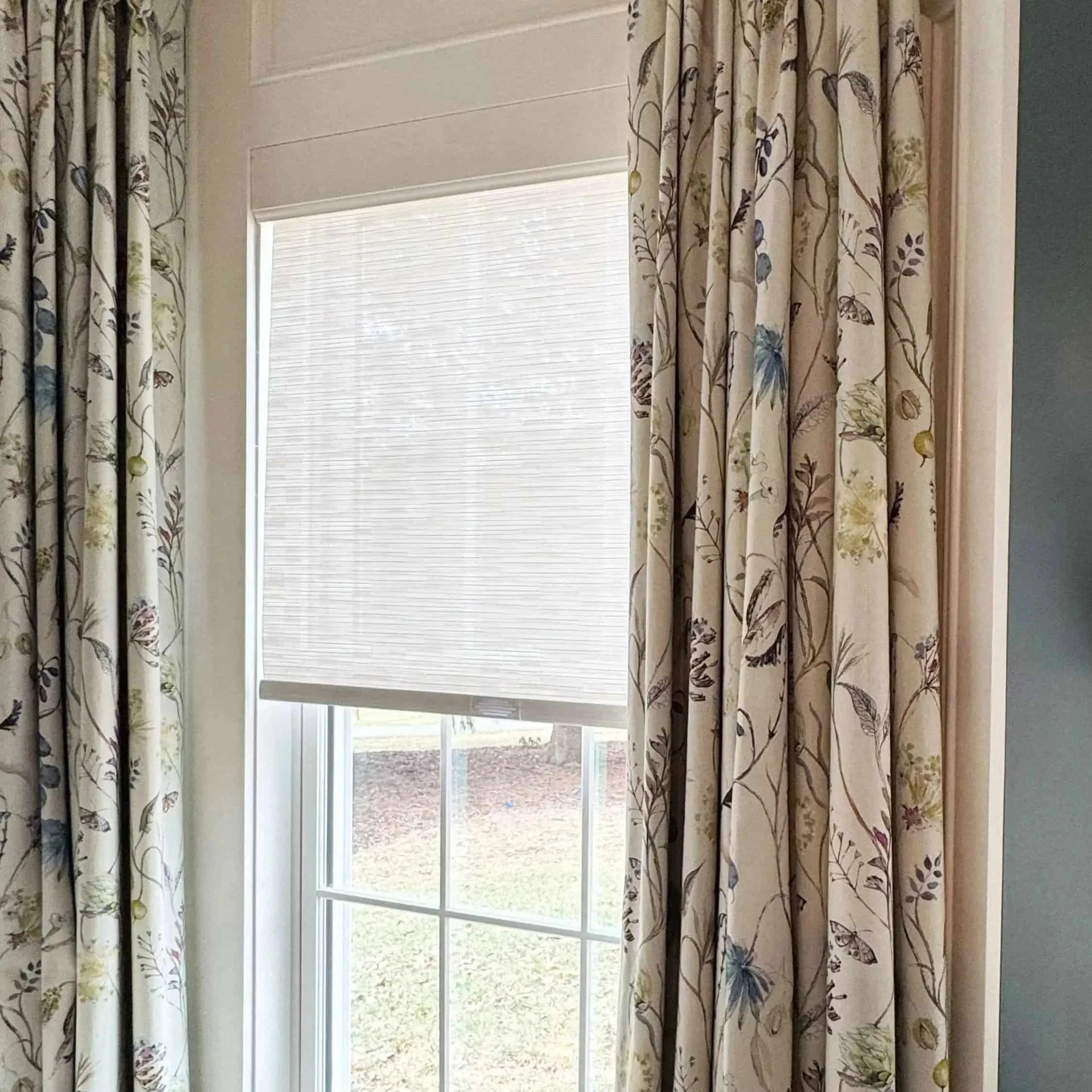Primary bedroom roller shade with custom floral drapery panels
