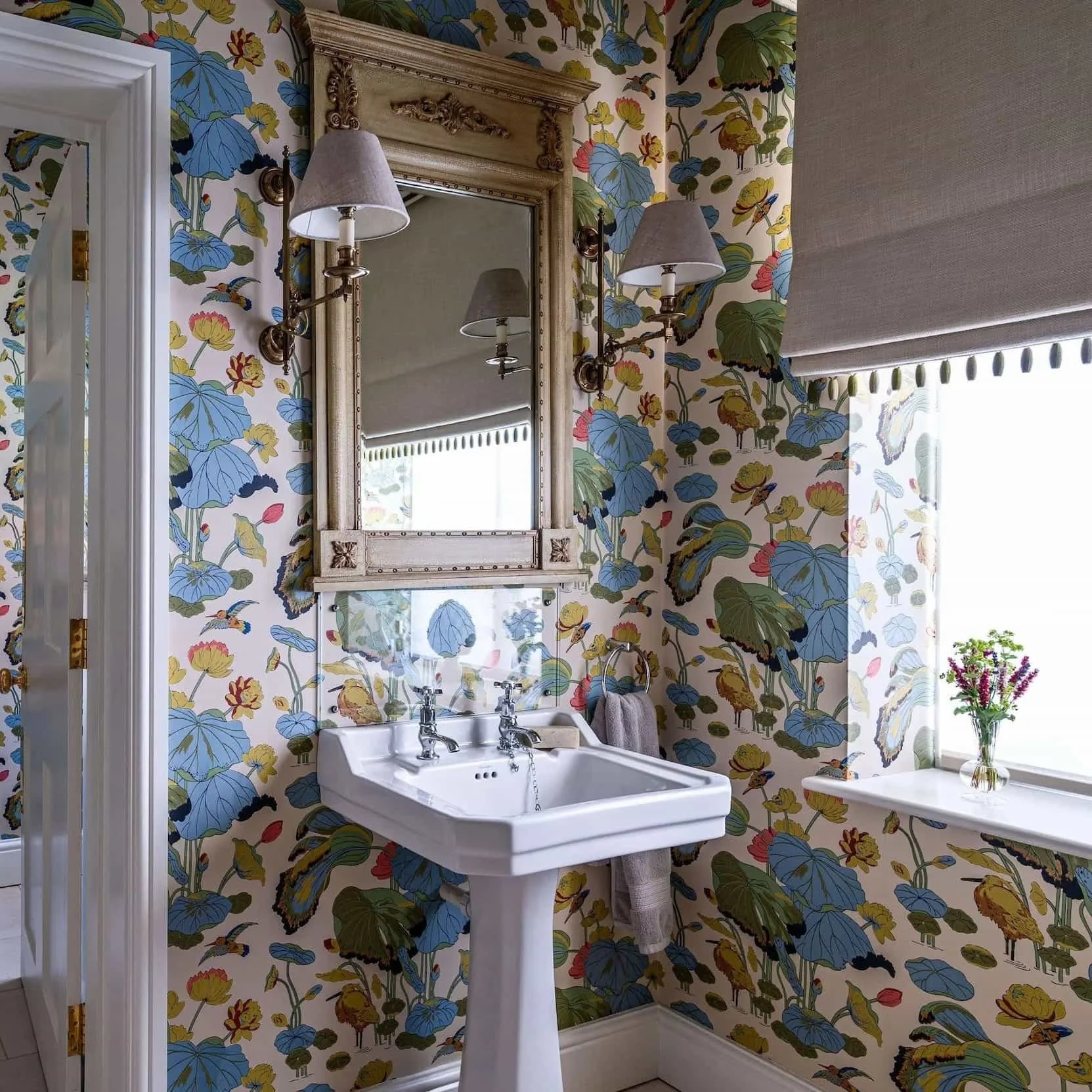 Custom beige Roman shade in a powder room with fun, colorful wallpaper
