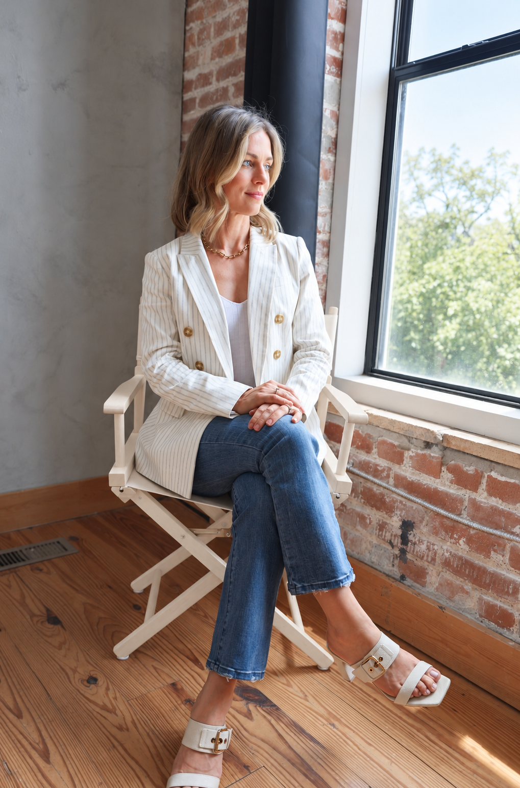 Jasmine Chambers, author of Dreams That Matter, seated beside a window in a white shirt and striped blazer.
