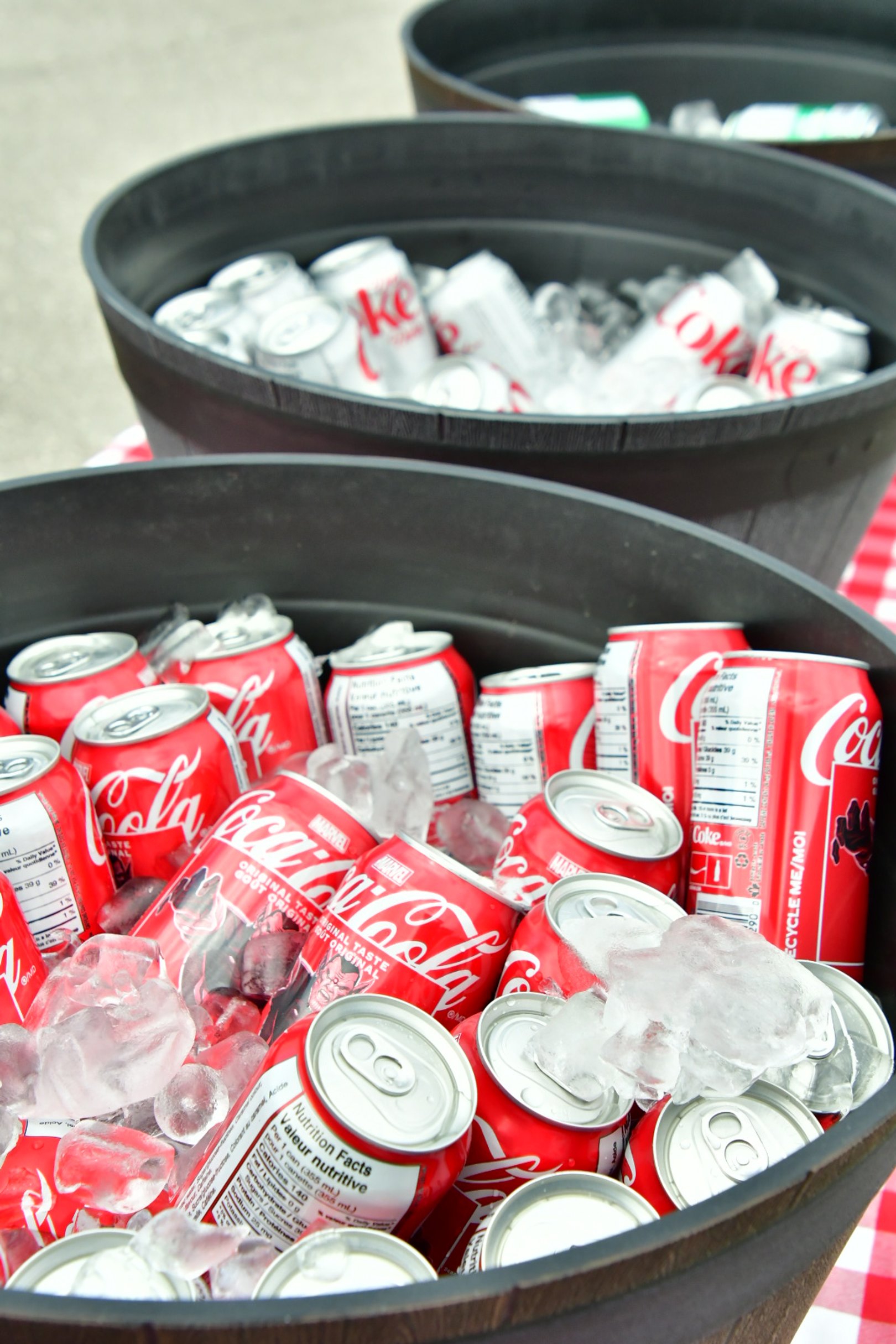 Multiple cans of Coca-Cola and Coke Zero on ice in black tubs.