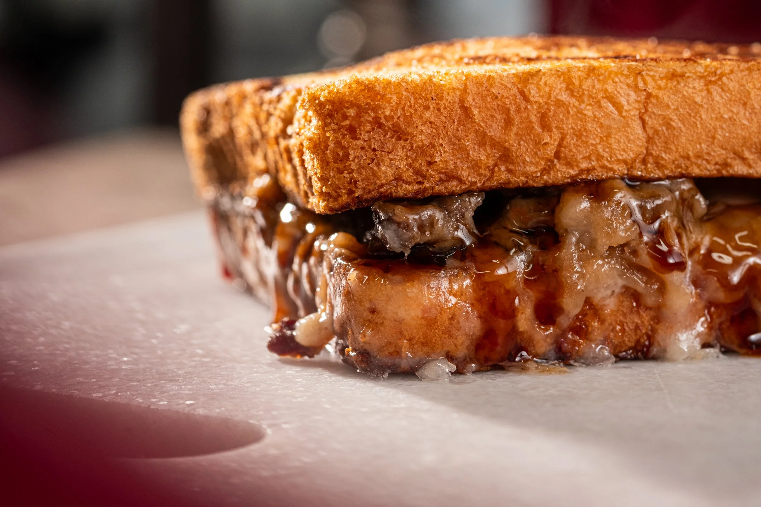 Close-up of a grilled french toast sandwich with oozing syrup.