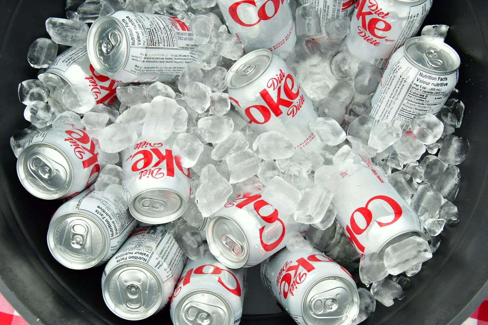 Cans of Diet Coke ice cold in a black bucket with ice cubes.