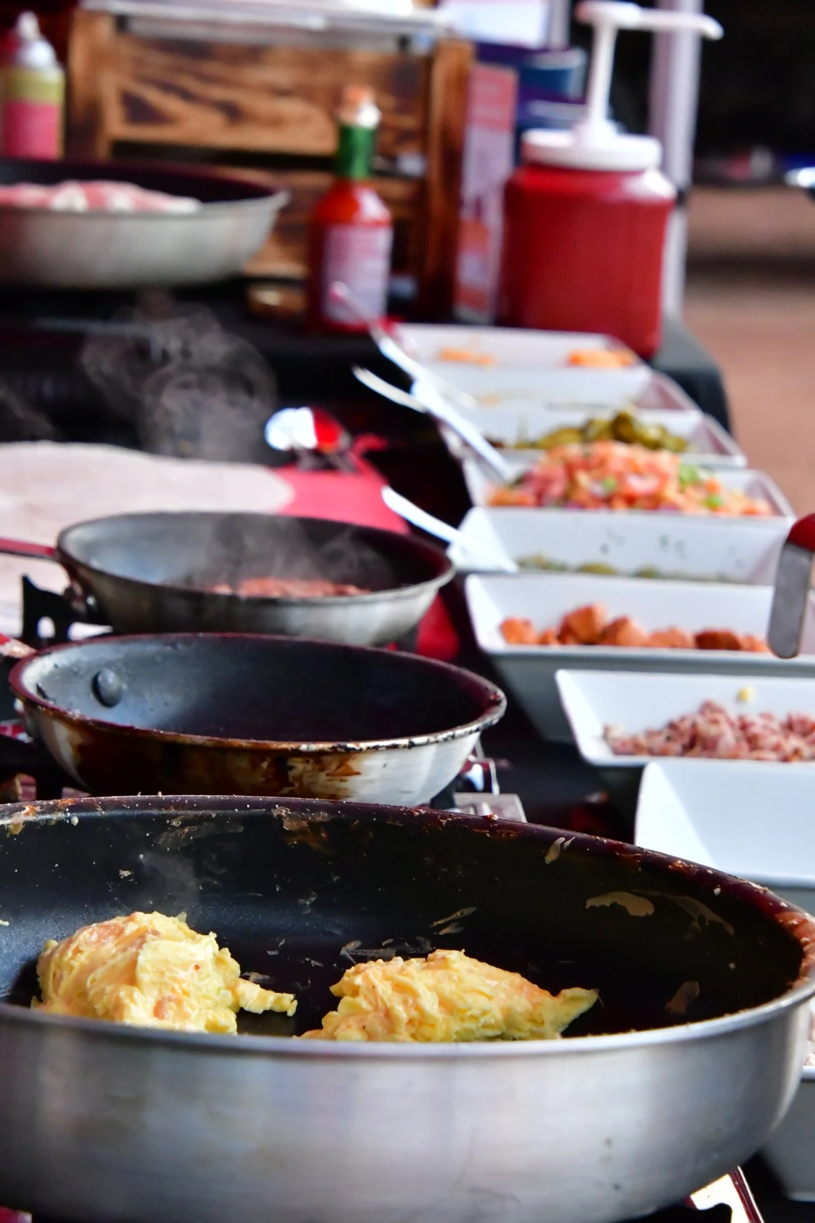 Build your own burrito bar featuring white bowls of various toppings and pans for cooking.