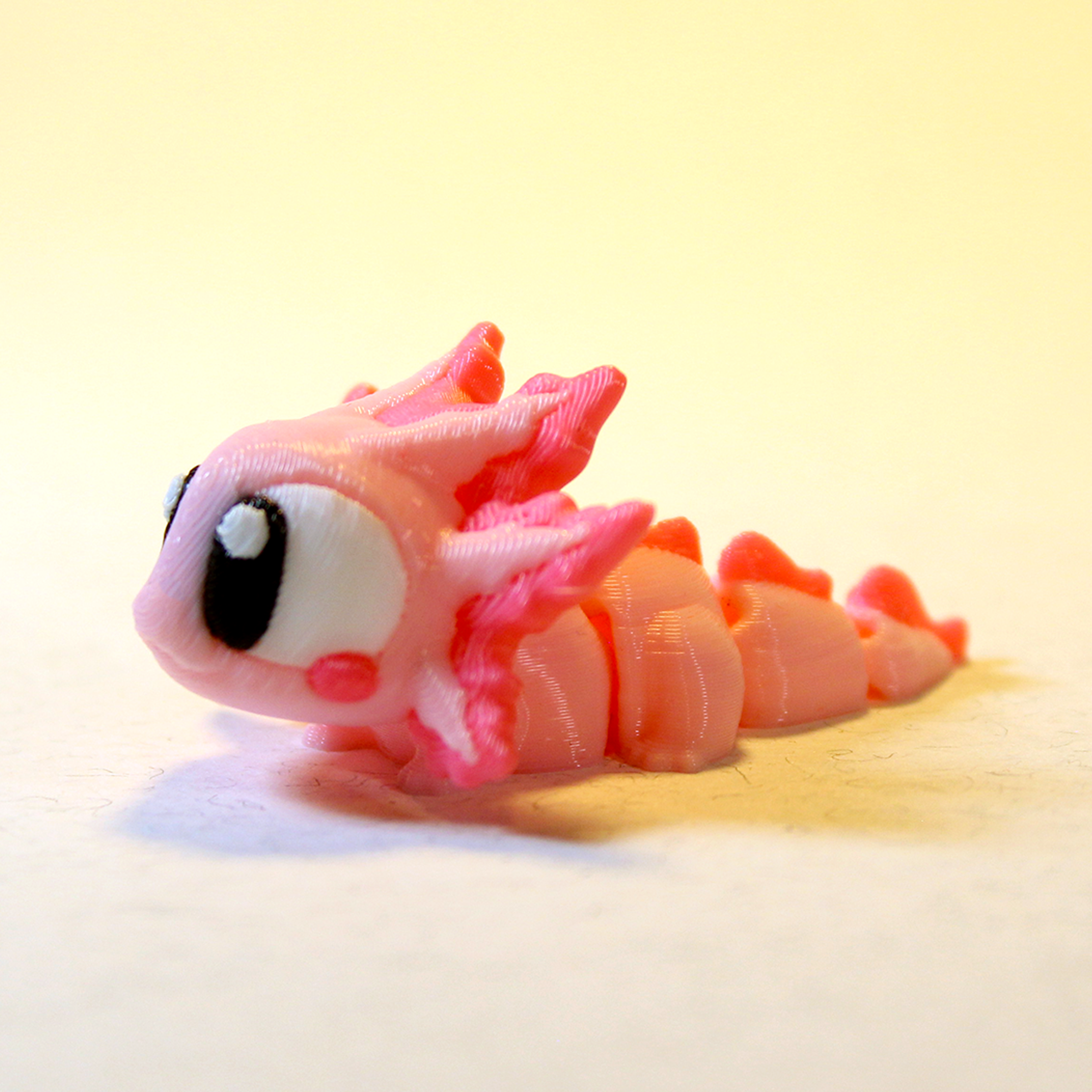 Adorable pink Zigglie Axolotl toy with stripey tail and smiling eyes, great for gifting or display