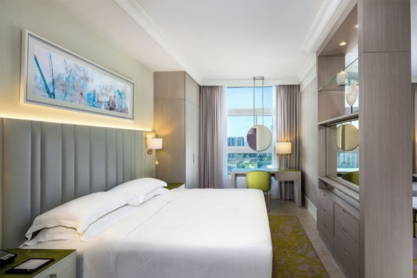 guestroom at beach rotana - all suites with one bed and city views through a large window