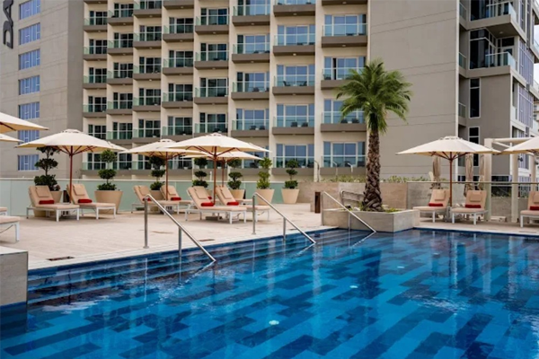 damac hills 2 hotel pool with lounge chairs and umbrellas in the background