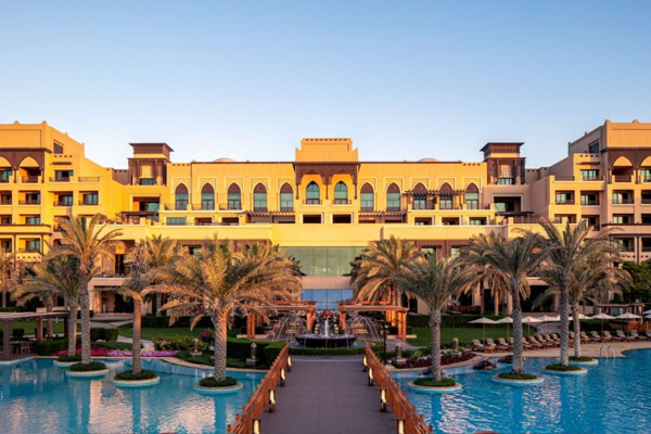 exterior view of saadiyat rotana resort and villas with walkway, palm trees and surrounding water