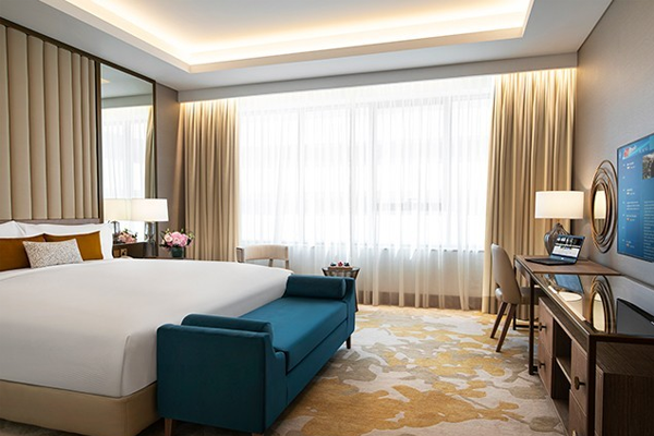al jaddaf rotana suite hotel guestroom with a king bed, dresser and seating area