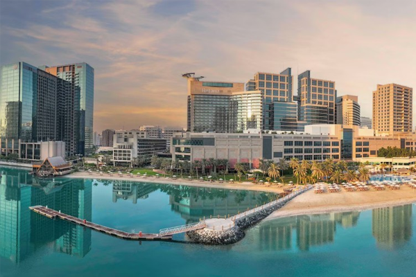 waterfront exterior view of beach rotana with sandy beach and lounge chairs