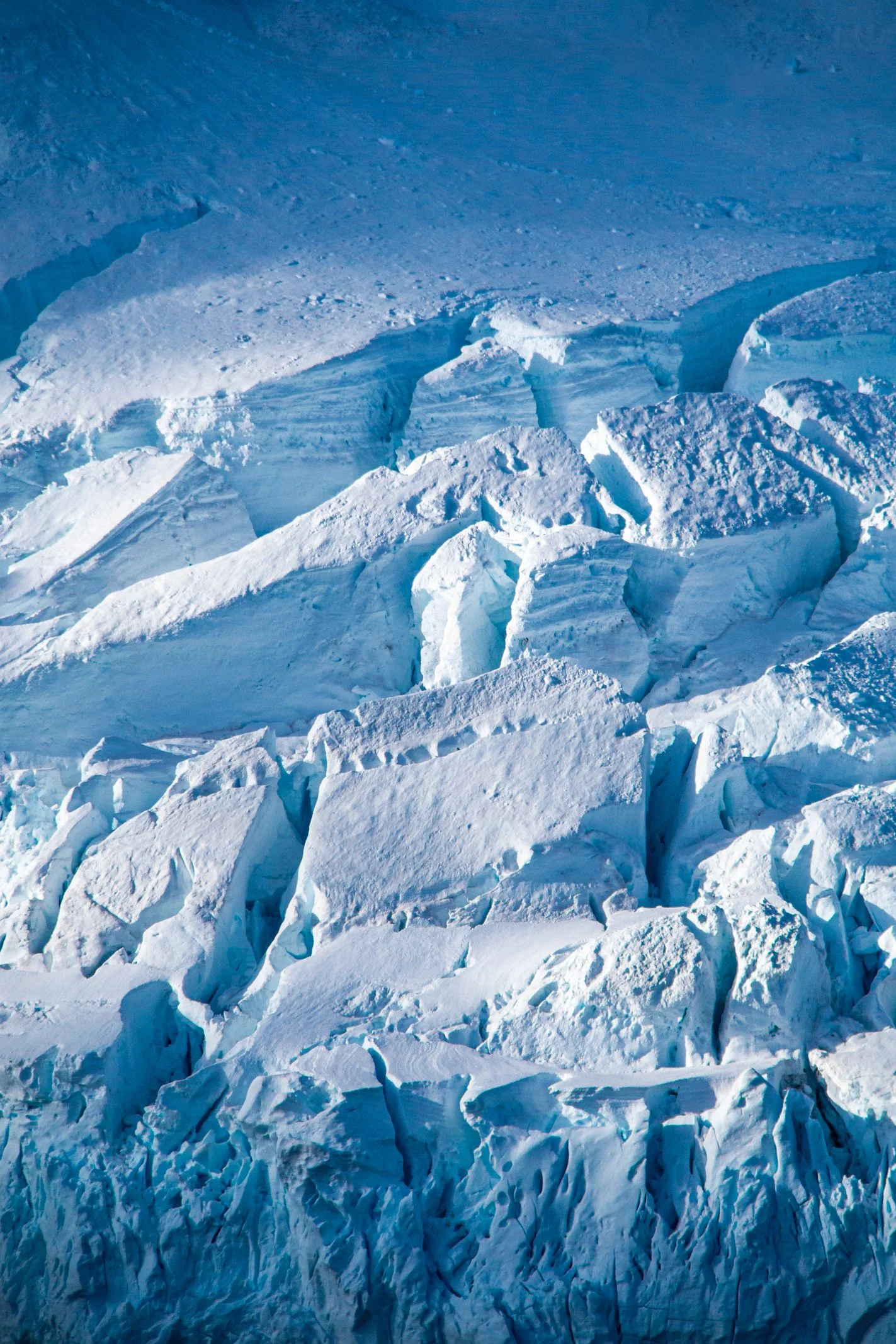 Close-up of large, jagged chunks of ice and snow on a glacier, with shades of blue and white.