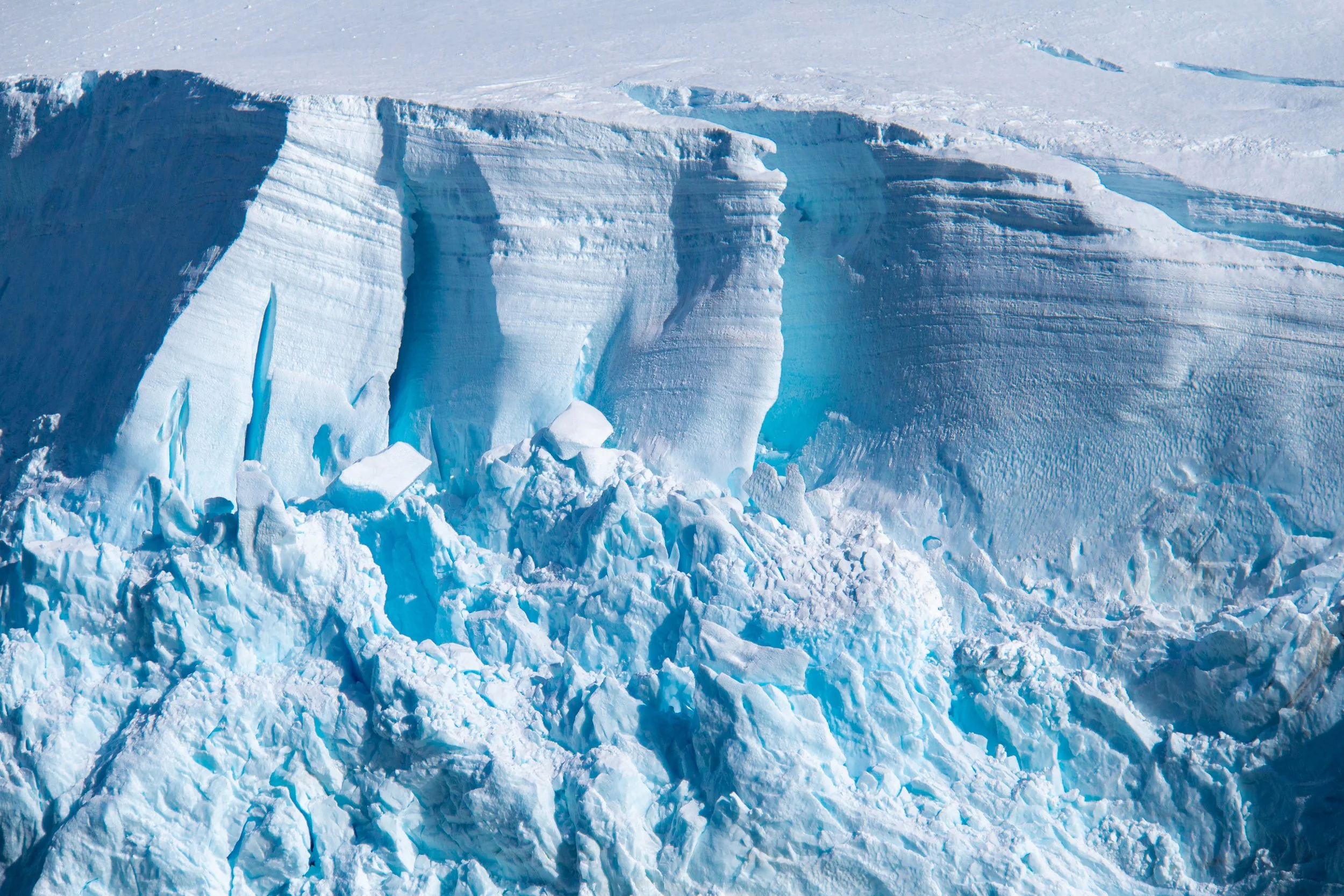 A large glacier with blue ice and jagged icebergs breaking off from the main ice formation.