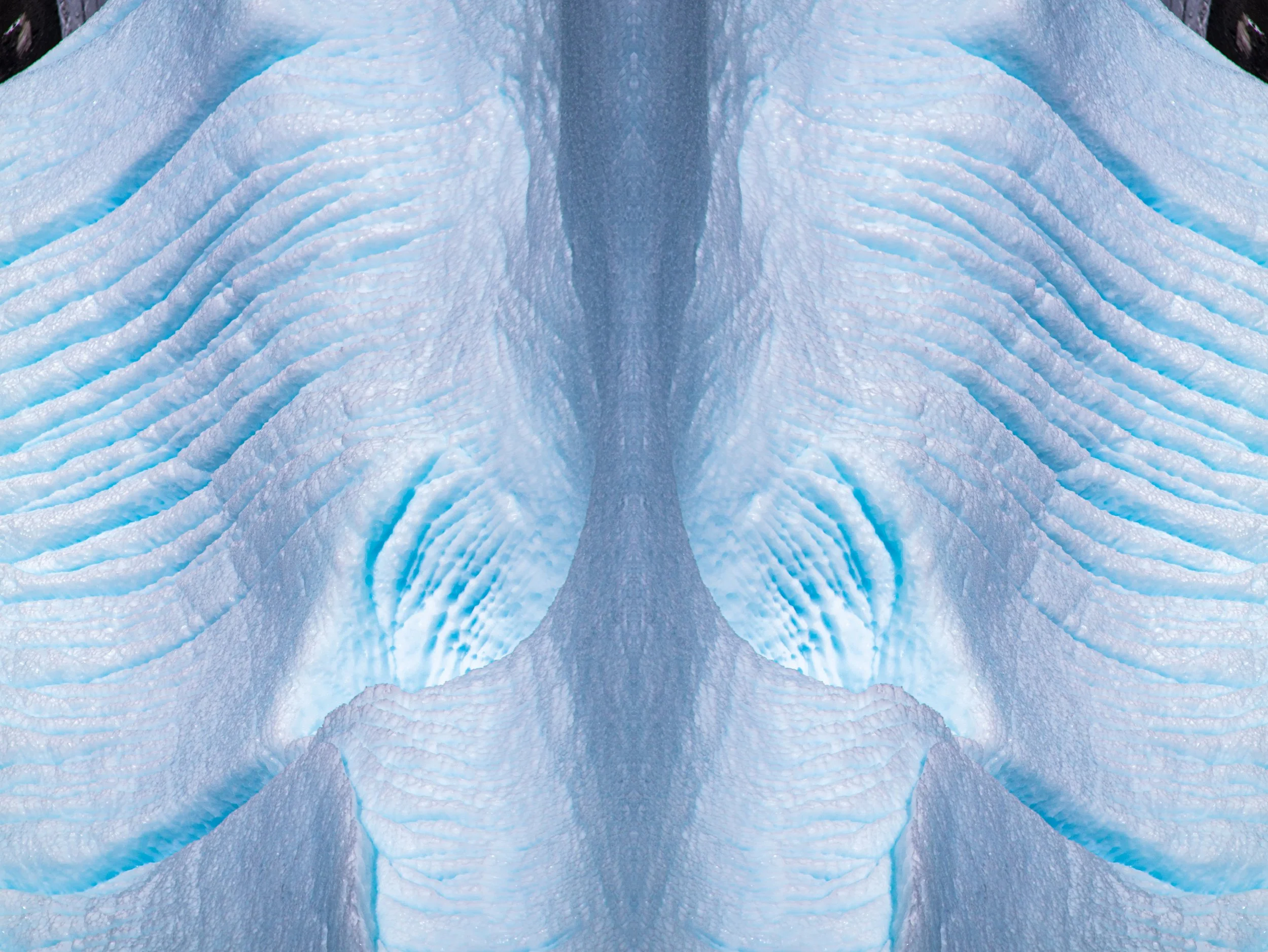 Aerial view of a glacier with crevasses, showing layers of blue and white ice.