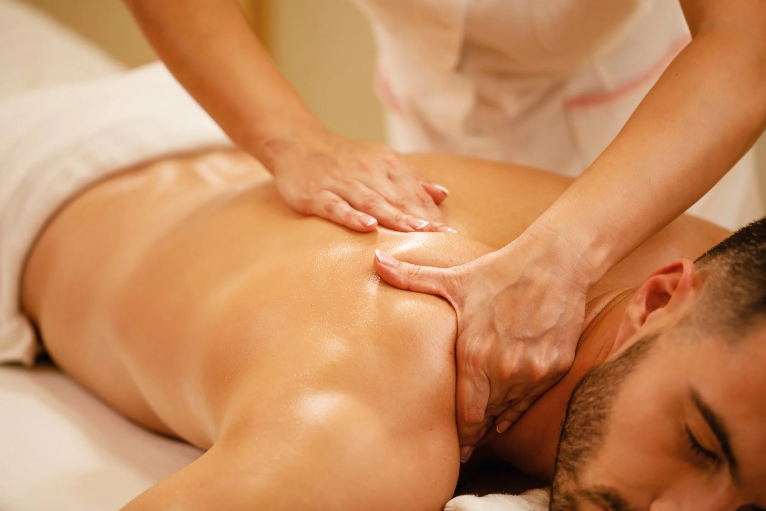 A person receiving a back massage from a massage therapist in a spa setting.