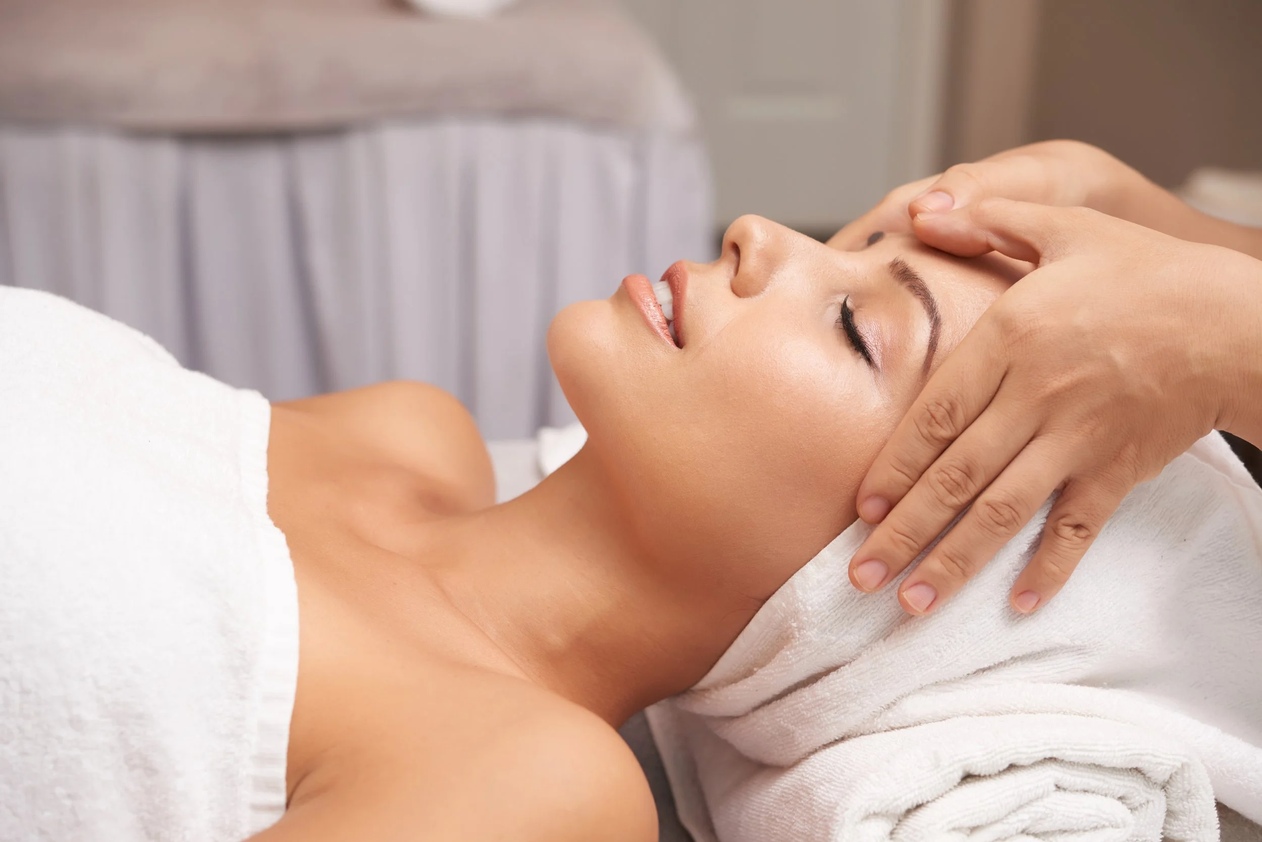 A woman receiving a facial massage at a spa.