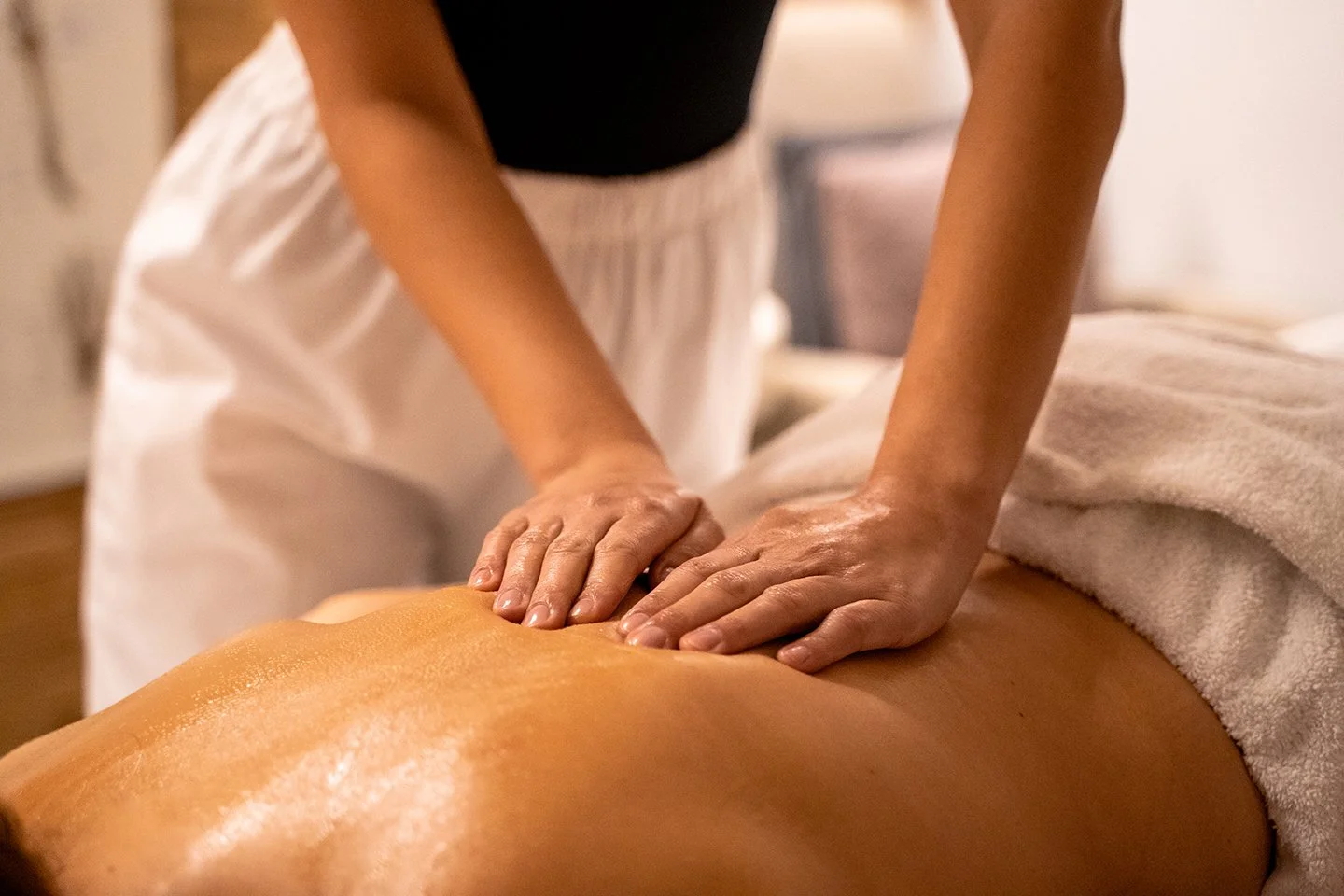 A person receiving a massage on their back in a spa setting.