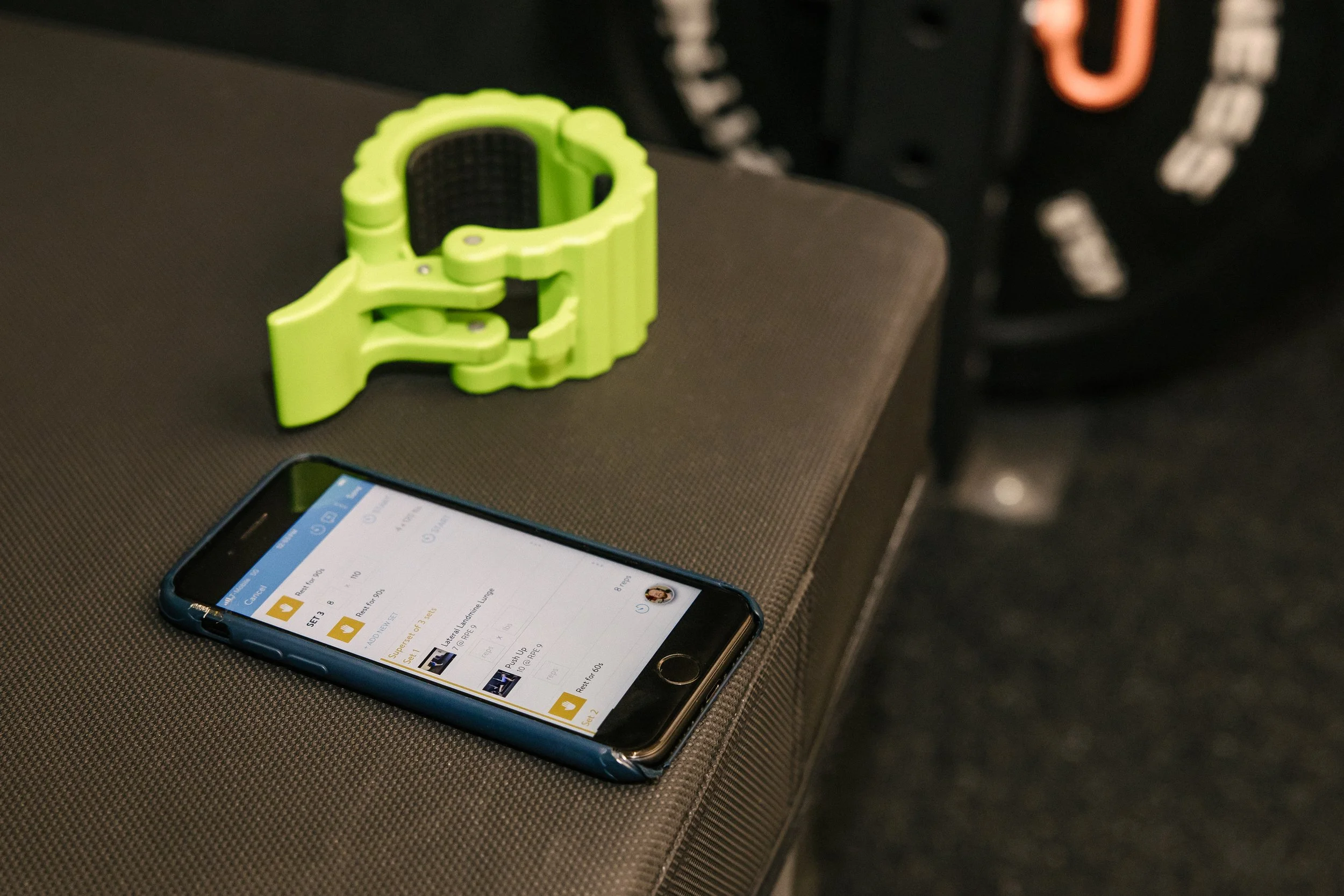 A smartphone with a calendar app open and a green object on a dark gray bench.