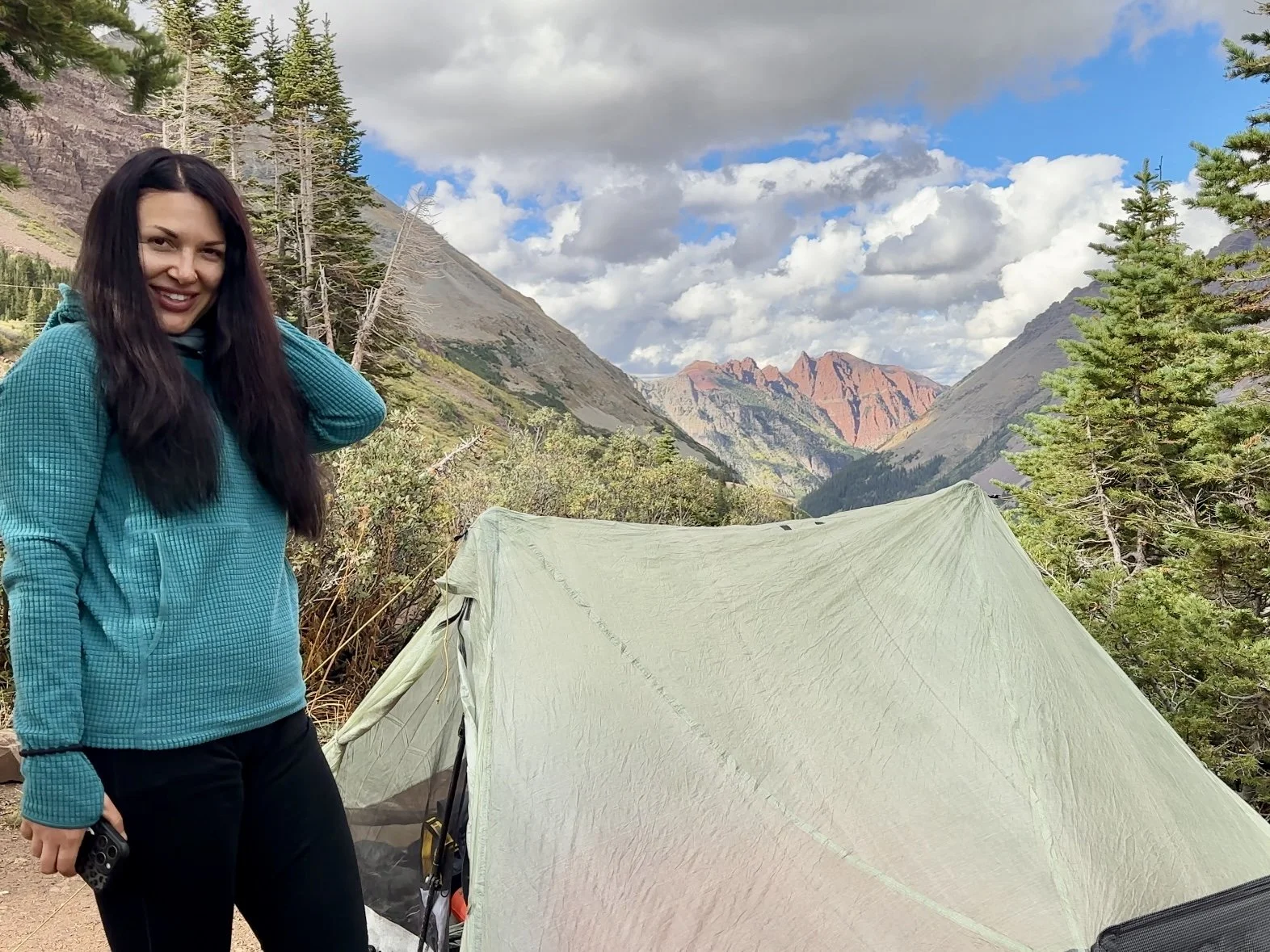 Beautiful hiker in front of a tent surrounded by mountains on the Four Pass Loop in Colorado