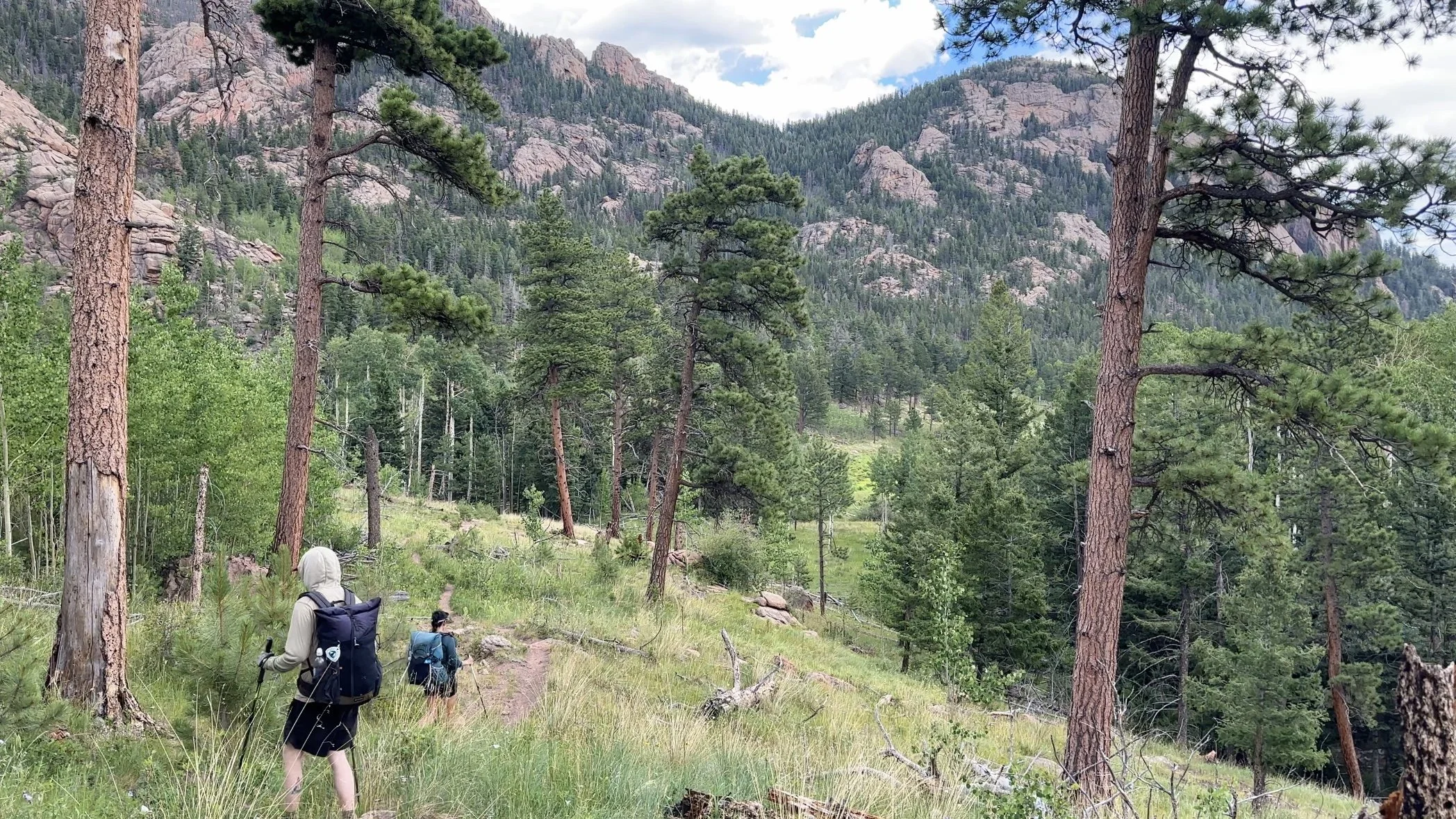 Two backpackers hiking downhill with beautiful mountain scenery in the Lost Creek Wilderness
