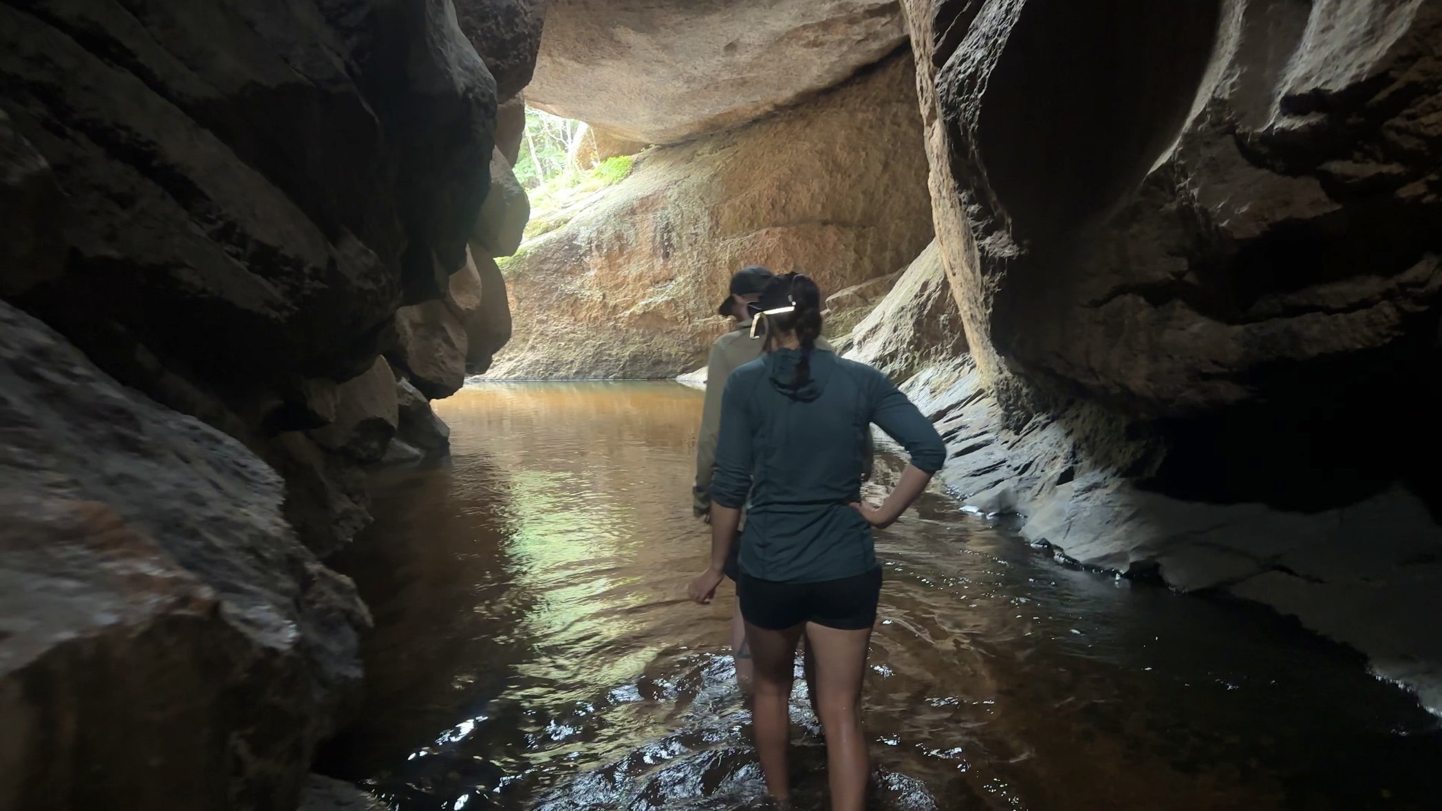 Hikers wading through a creek in a cave