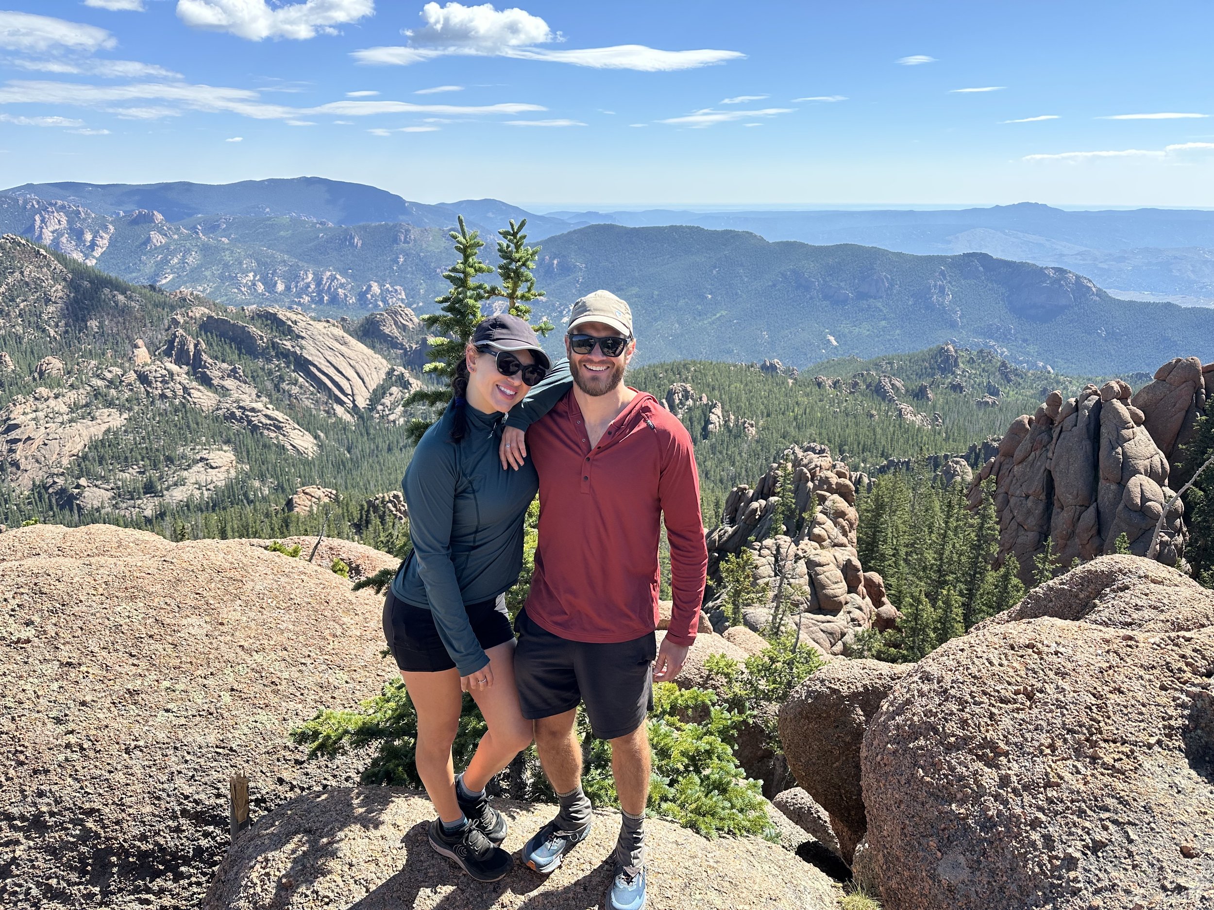 Two hikers standing on a rock outcropping with beautiful views of the Rocky Mountain Wilderness