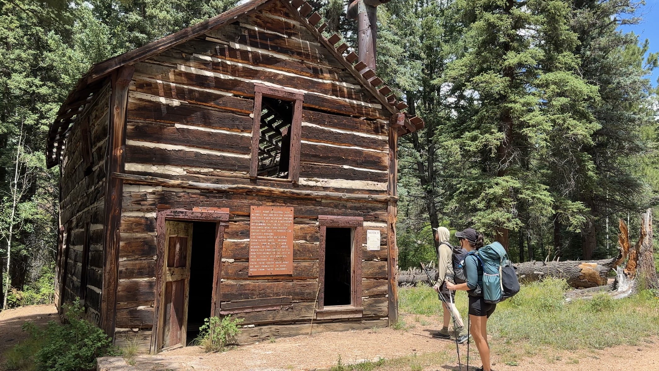 Backpackers in the forest looking at a ruins. Shaft house.