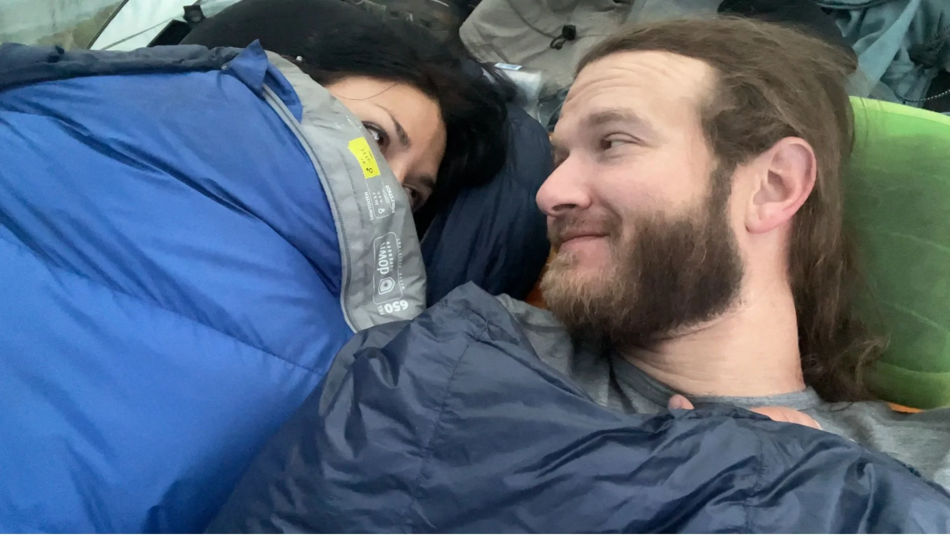 Two backpackers bundled up in sleeping bags while camping