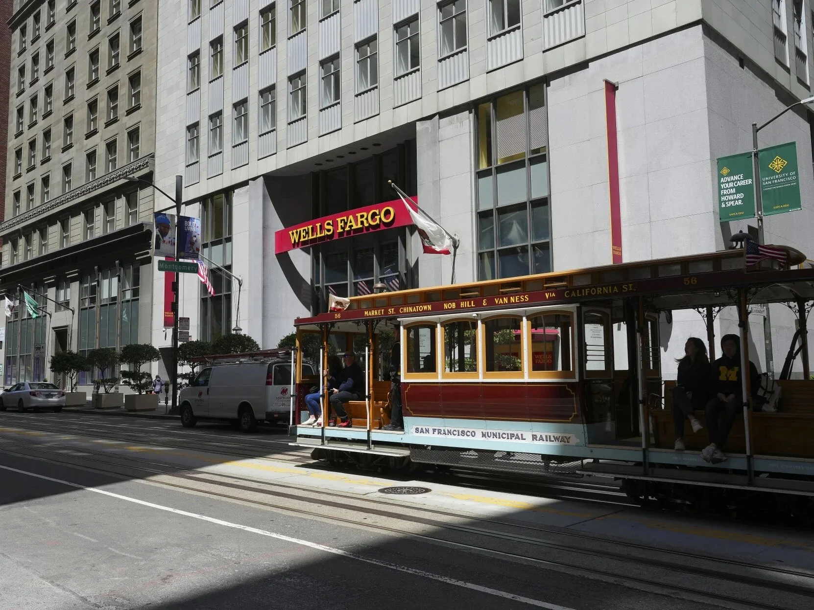 A cable car rolling in front of a Wells Fargo building in San Francisco.