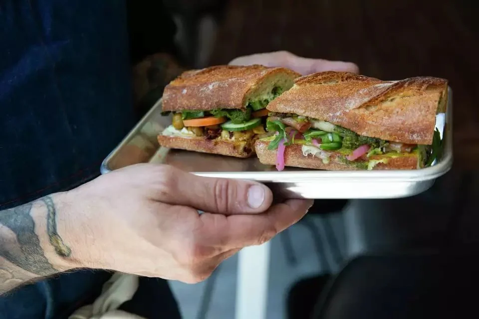 Owner Dario Barbone holds two of his signature paninis at Aurora Centro.