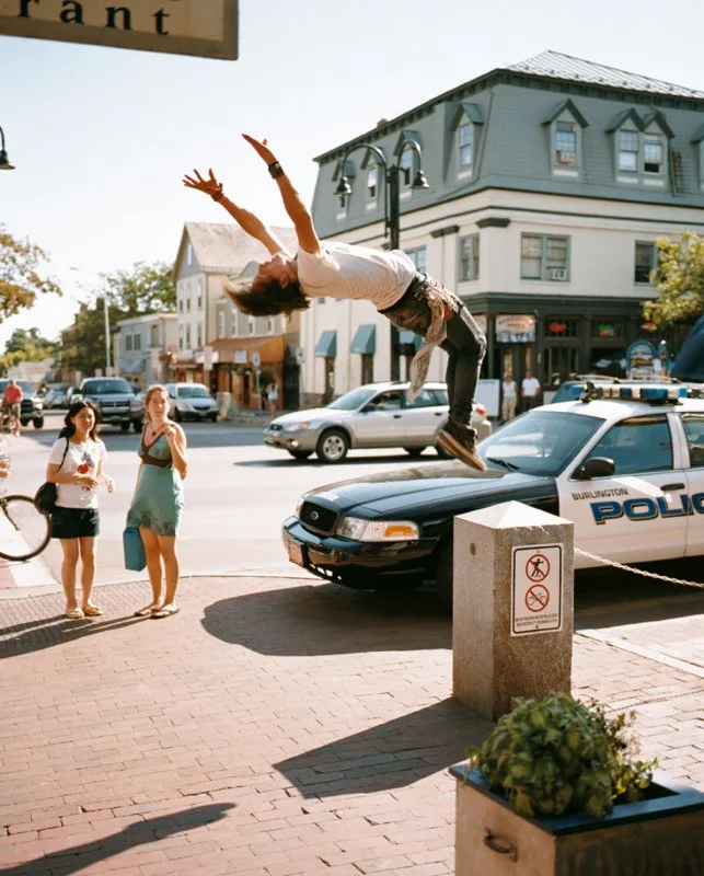 A man is doing a backflip on a busy city street, with onlookers watching.