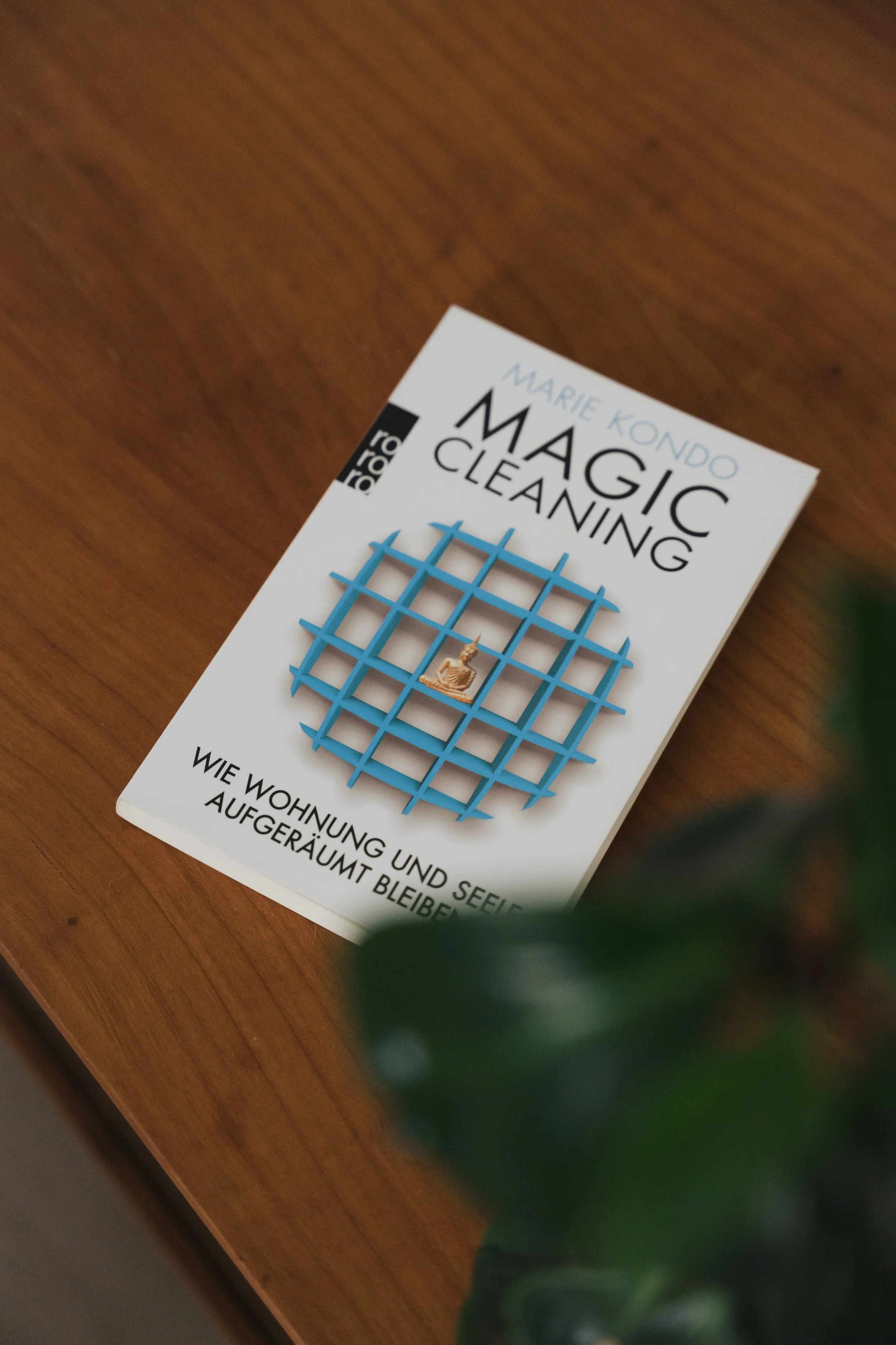 Buchcover mit Titel ‚Magic Cleaning‘ von Marie Kondo, zeigt ein Gitter und eine kleine Figur in der Mitte