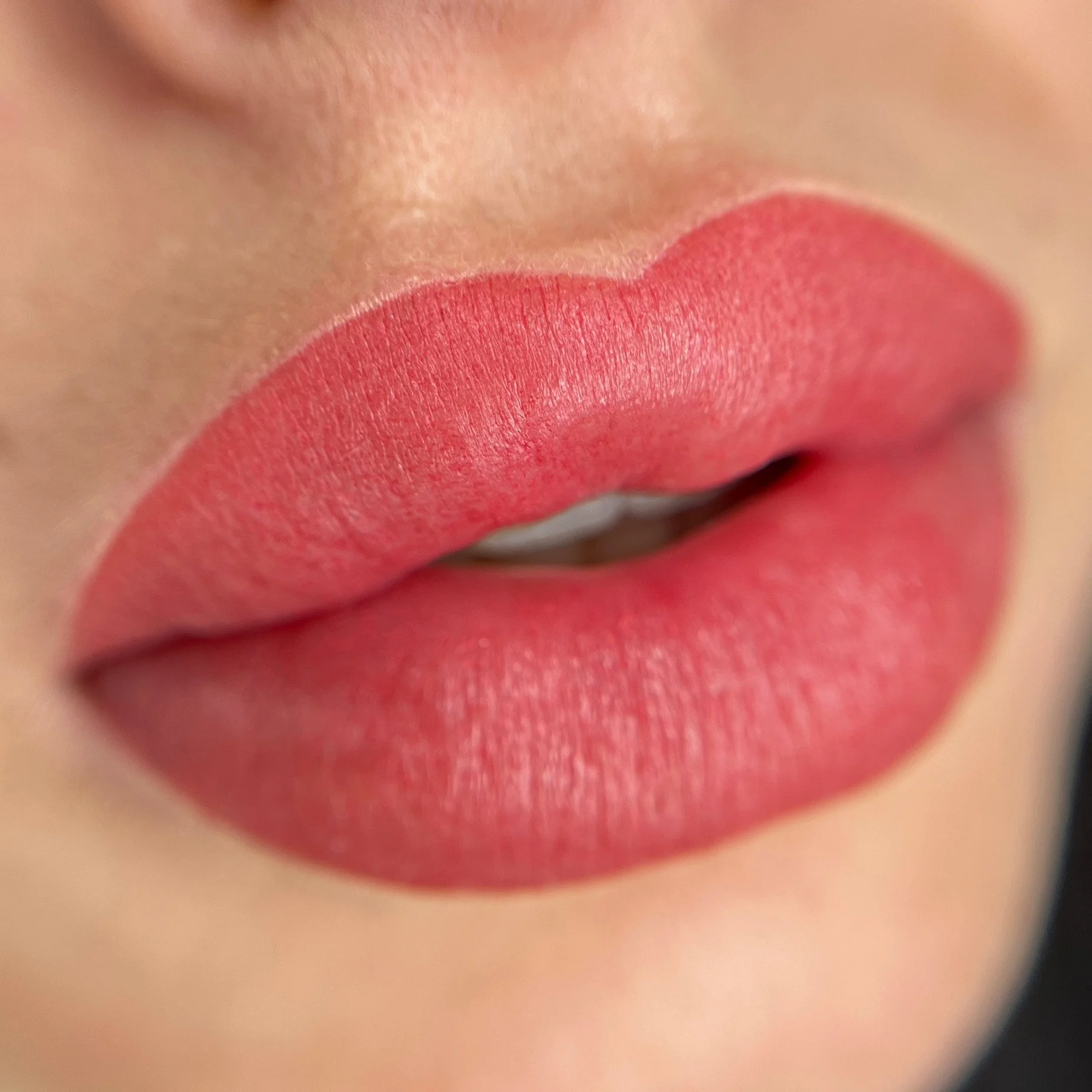 Close-up of lips with matte pink lipstick.