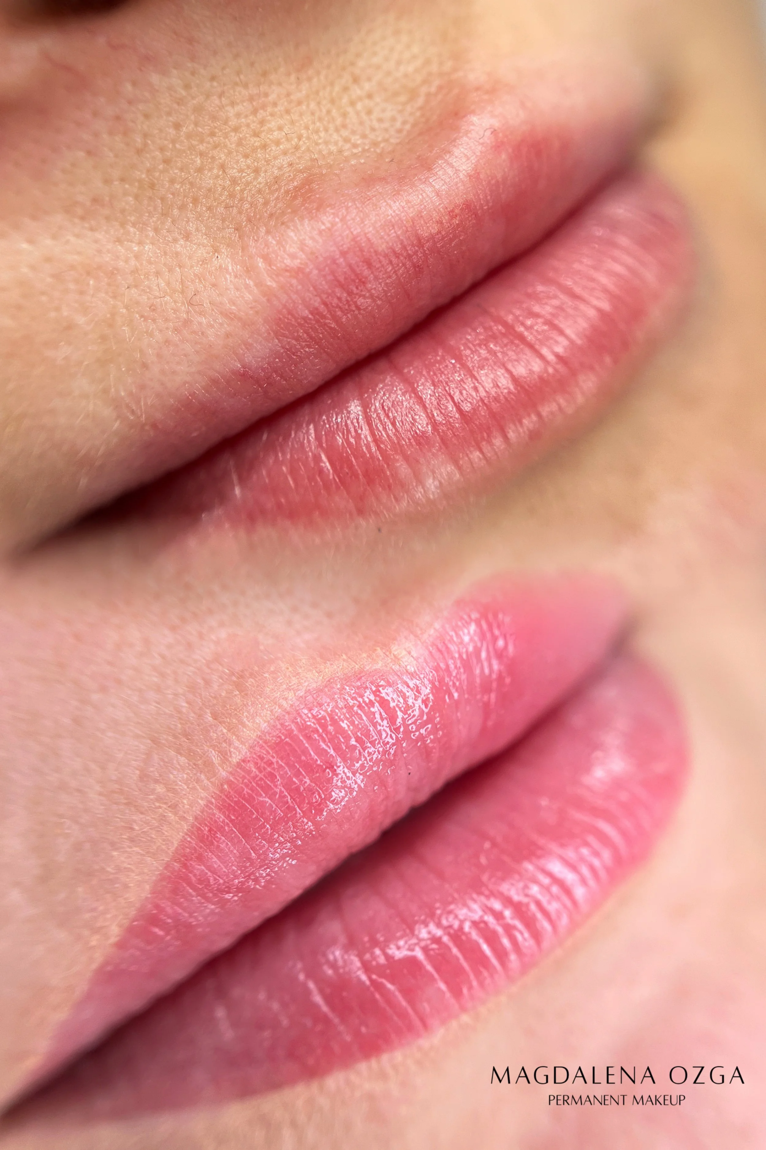 Close-up of pink lips with natural makeup, showing detailed texture and gloss. Text overlay reads 'Magdalena Ozga Permanent Makeup'.