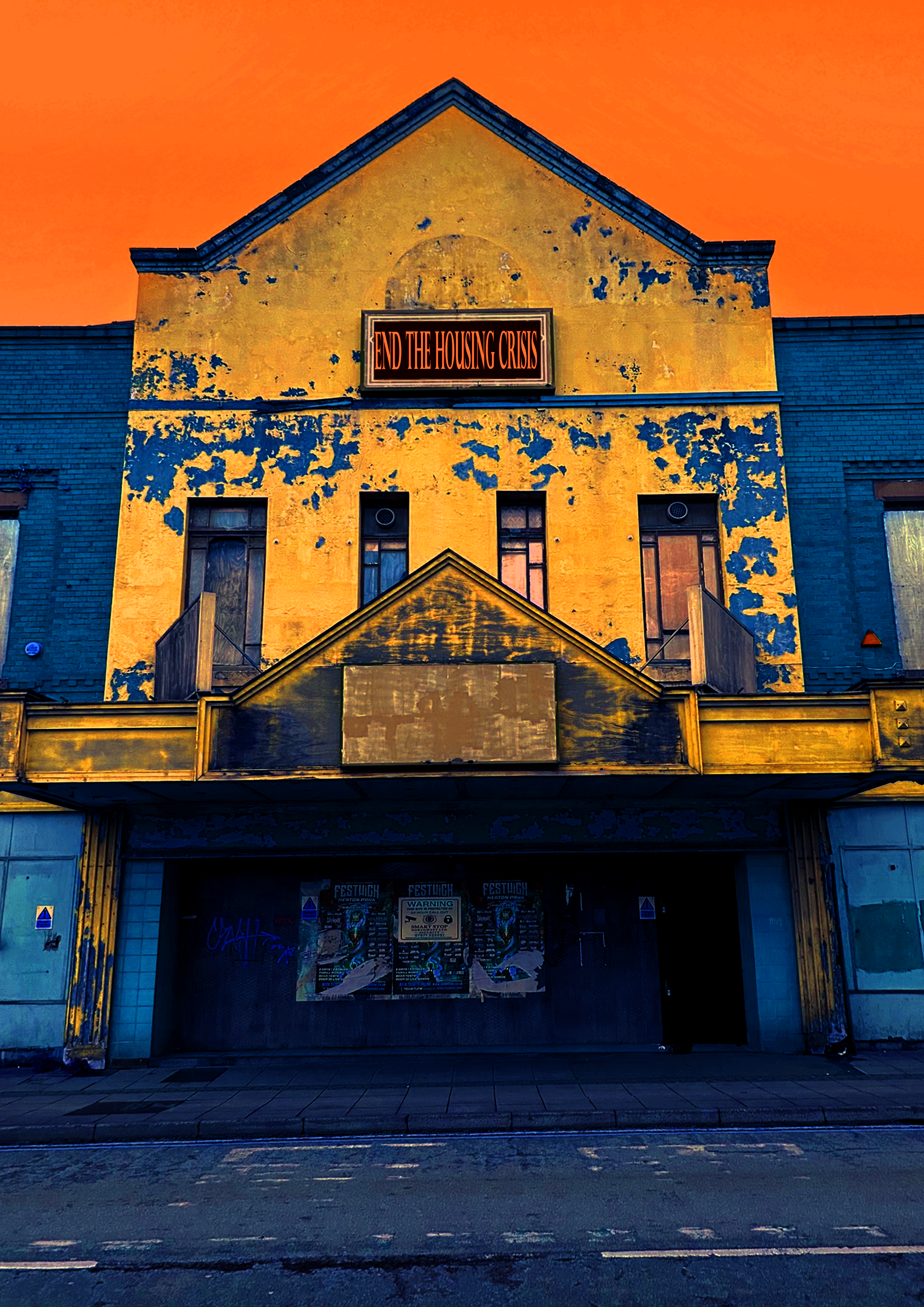 A run down building coloured vivid yellow and blue. There is a sign on it that reads ‘end the housing crisis’.