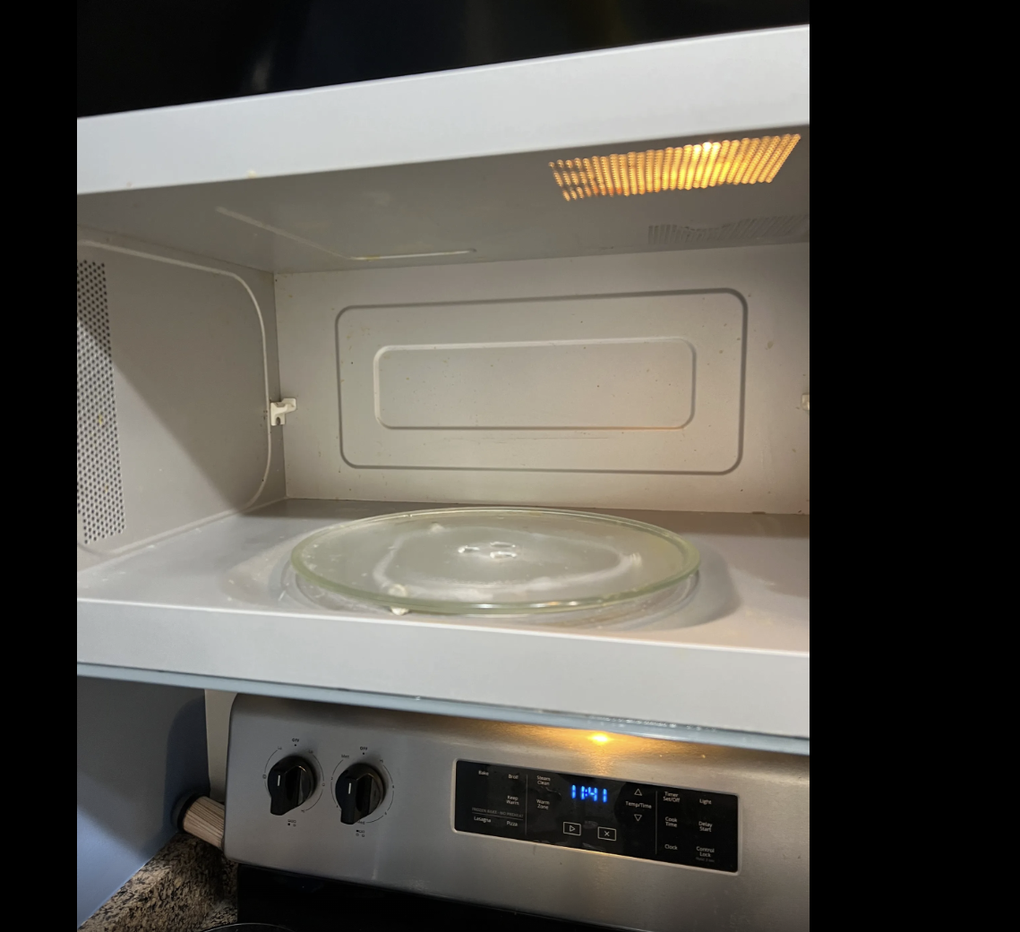 Empty microwave oven with a glass turntable inside, displaying the time of 1:41 on the digital clock.