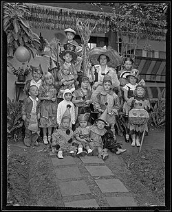 Photograph of children and one adult at a Halloween party dressed in a variety of Halloween costumes, circa 1935.