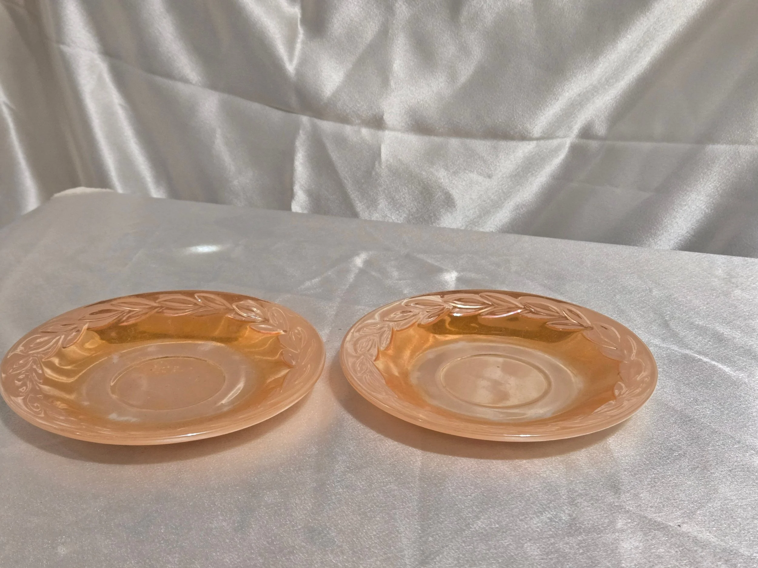 Set of Fire-King Peach Lustre saucers with iridescent sheen and vintage mid-century glow against white background.