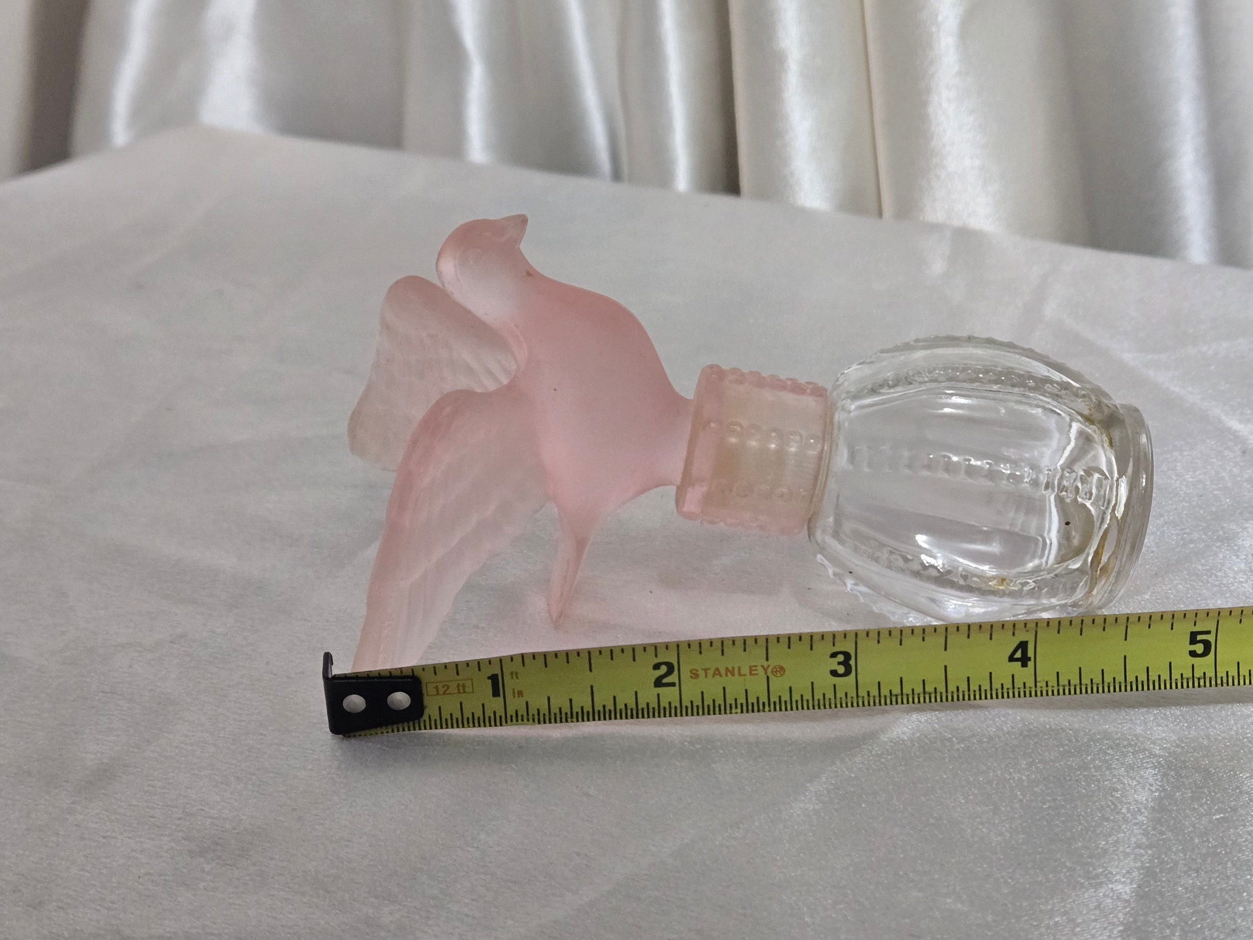 Vintage Avon pink dove perfume bottle shown with measuring tape to indicate size