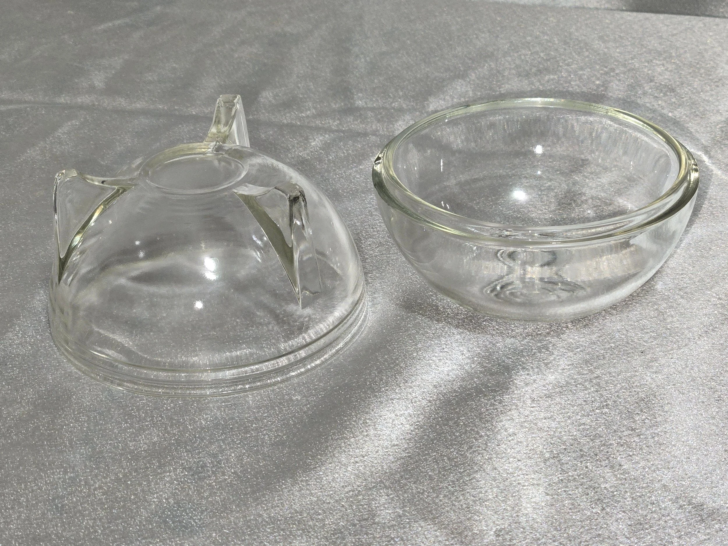 Vintage clear glass orb dish with rose embossed lid and three-footed base displayed on neutral background.