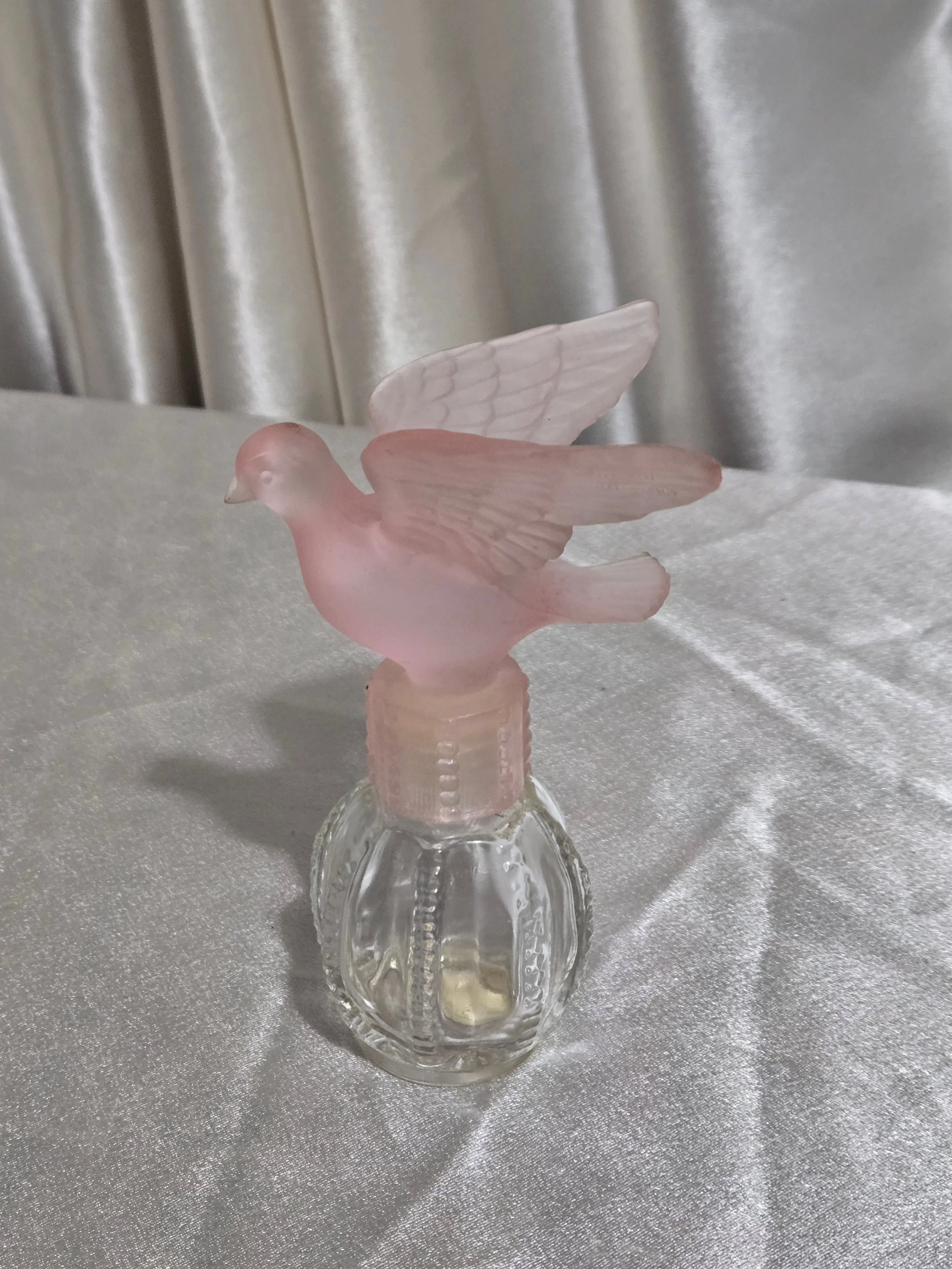 Close-up detail of frosted pink glass dove stopper on vintage Avon perfume bottle