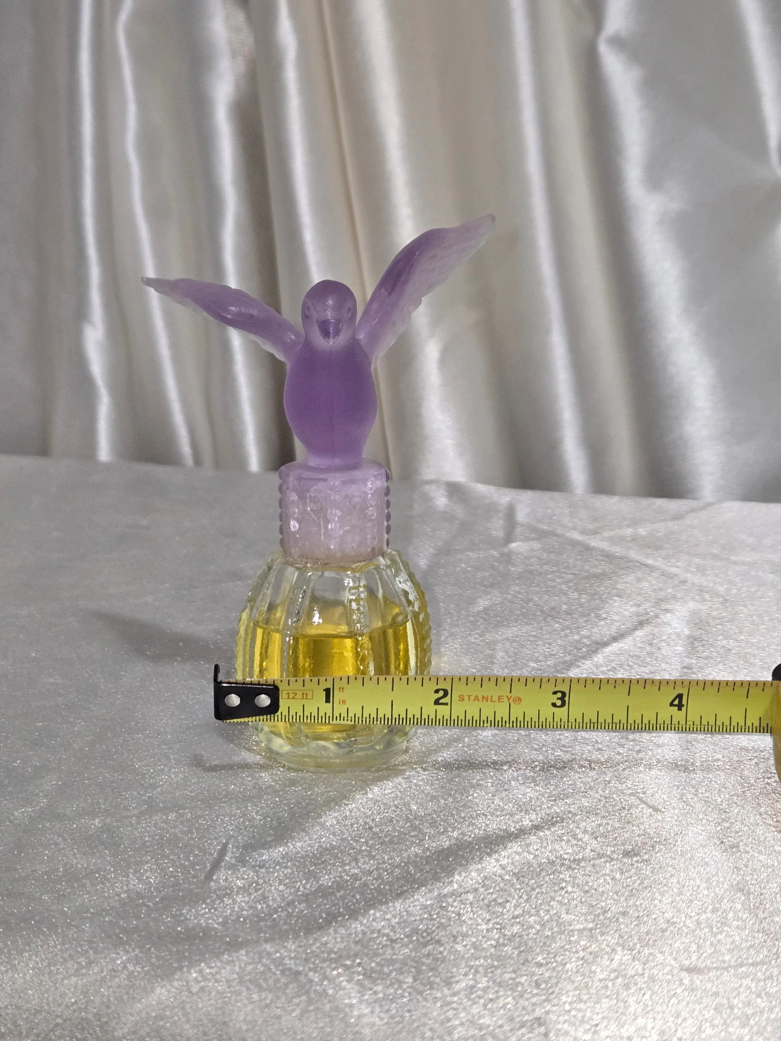 Close-up of frosted purple glass dove stopper on vintage Avon perfume bottle.