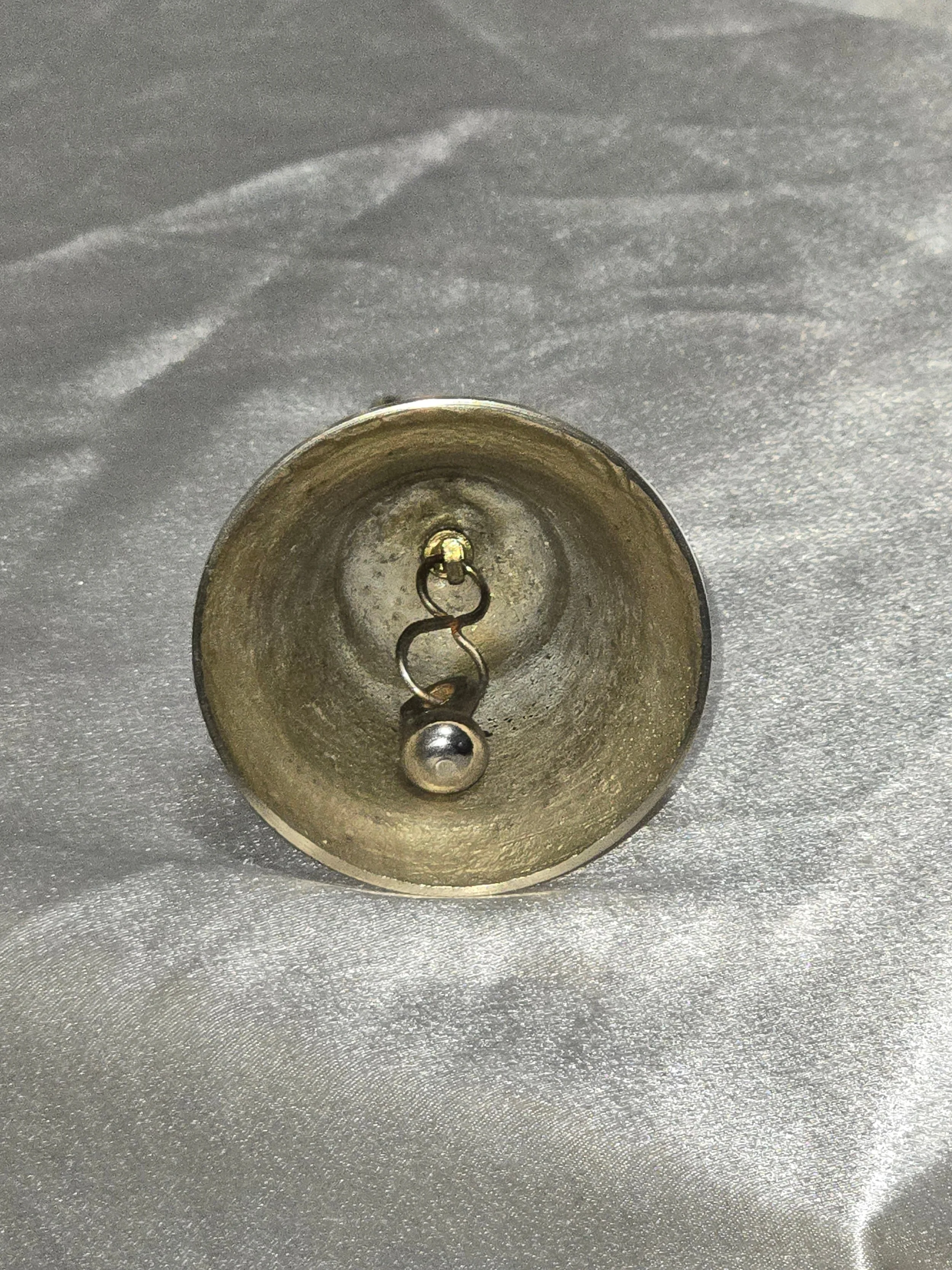 Close-up of vintage brass giraffe-shaped bell standing on silver background, 6 in tall mid-century safari collectible. Bottom view