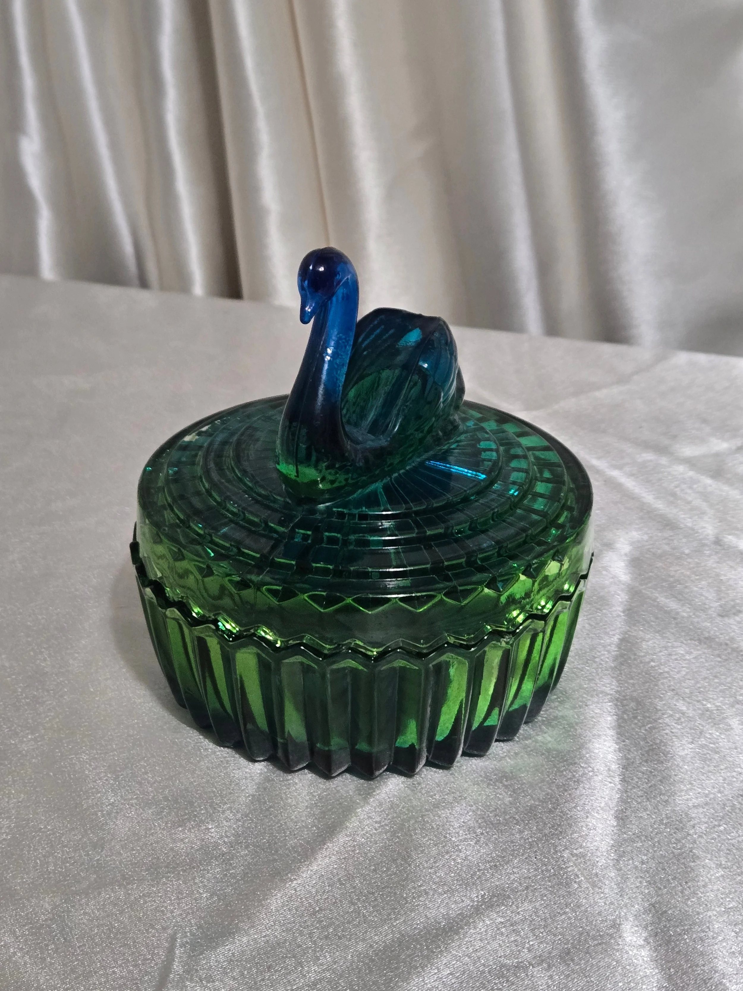 Close-up of swan figurine lid on vintage green glass candy dish.