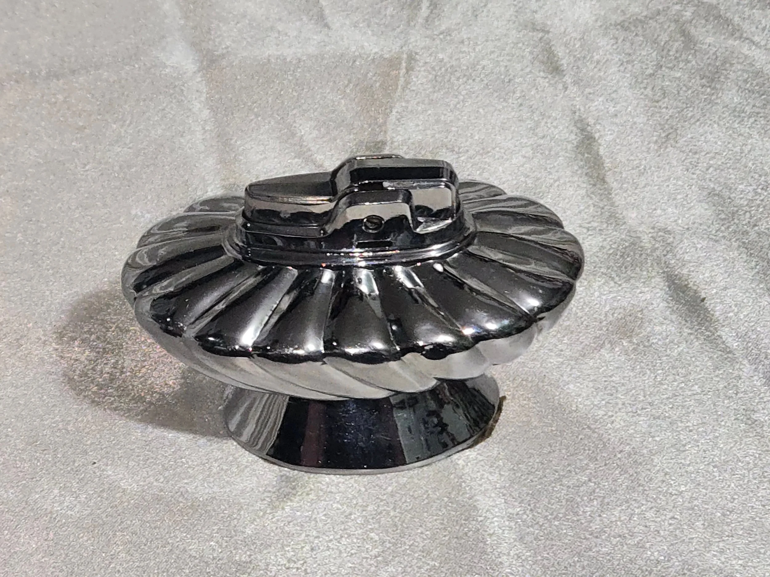 Vintage Ronson Regal chrome table lighter with swirl design, reflective silver finish, shown on silver backdrop.